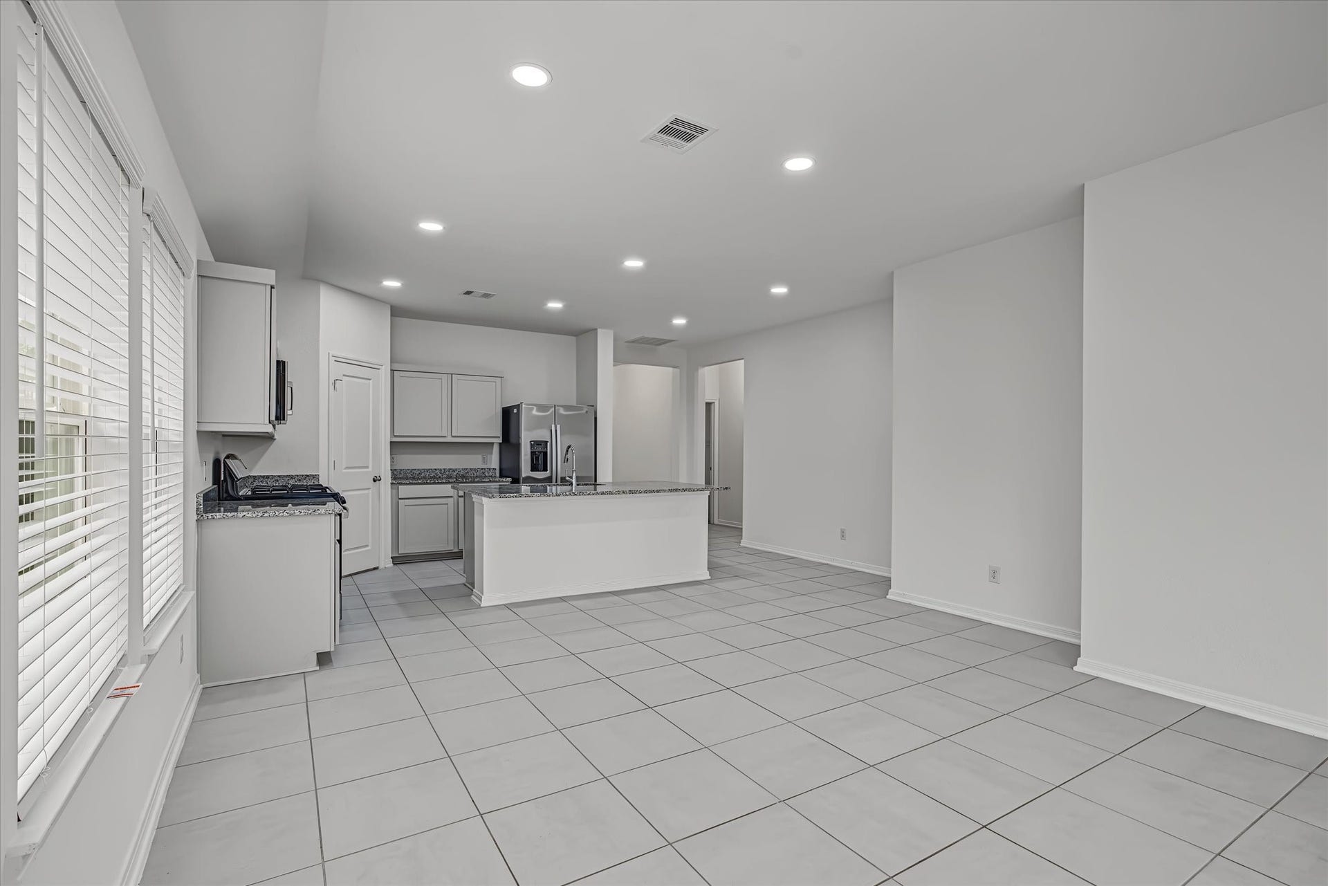 9607 Bright Song Lane, Houston, TX 77078 Spacious open-concept kitchen and living area with modern finishes, abundant natural light, and sleek tile flooring, perfect for entertaining.