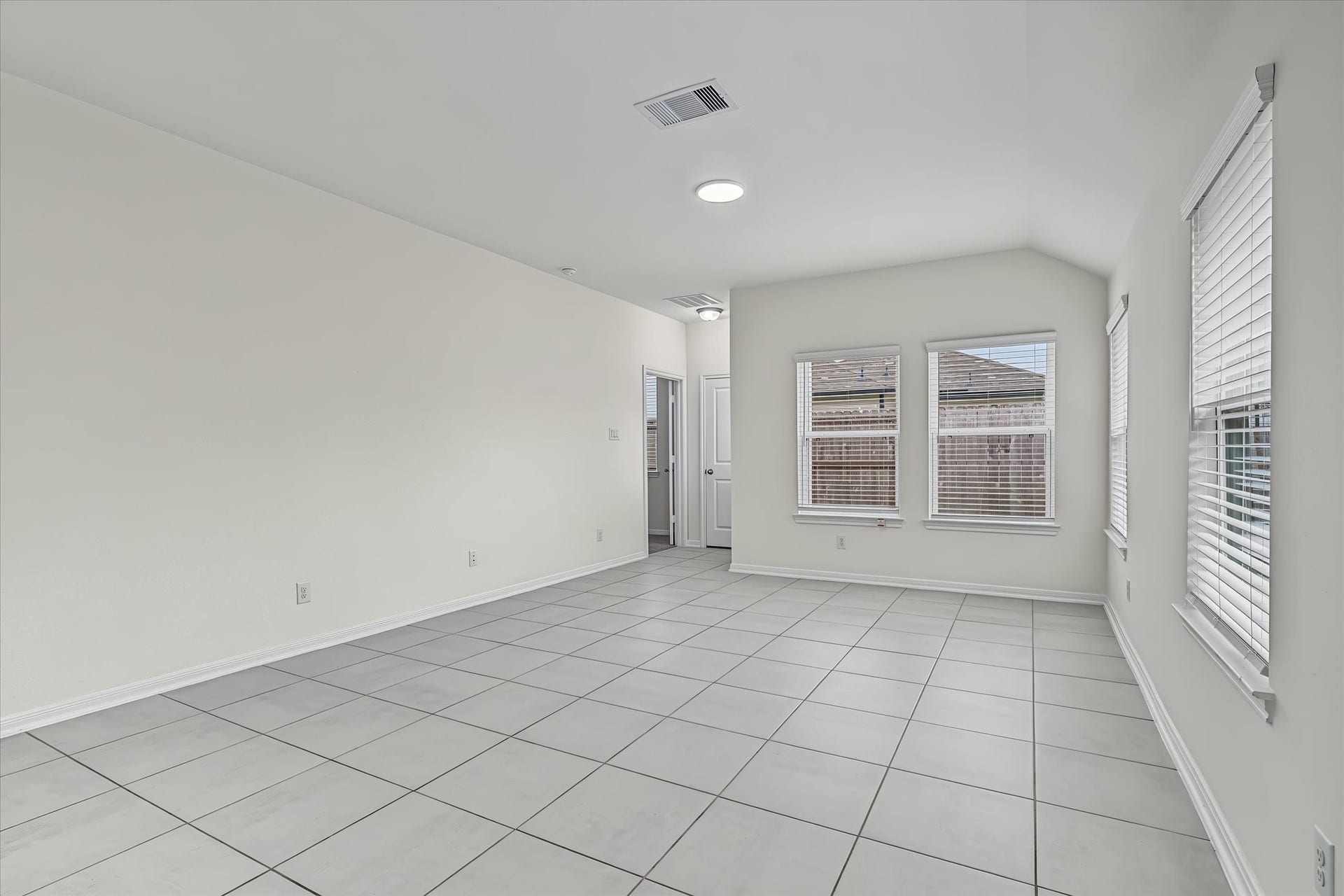 9607 Bright Song Lane, Houston, TX 77078 Bright and spacious room with neutral tiles and abundant natural light from multiple windows, offering a versatile living space.