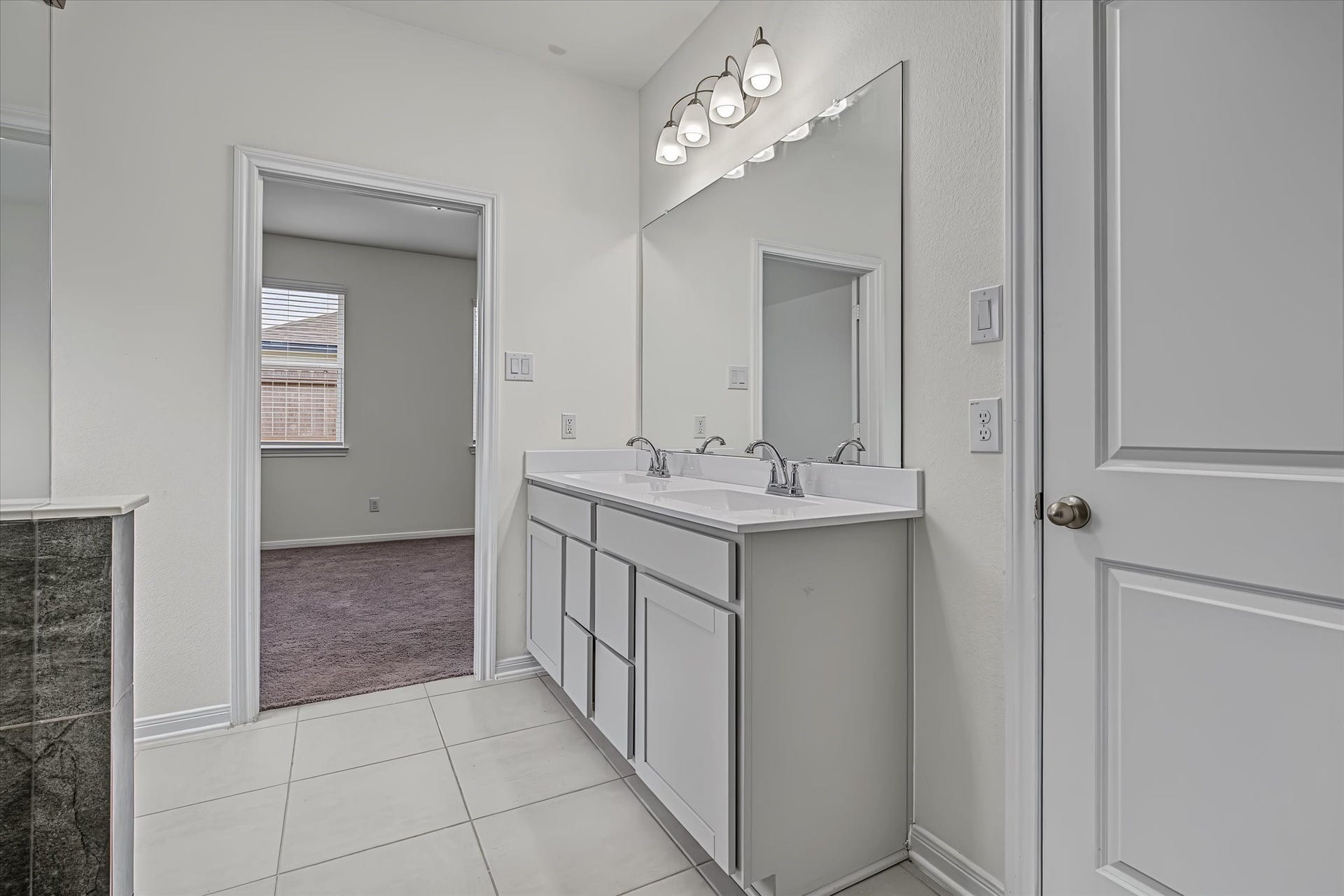 9607 Bright Song Lane, Houston, TX 77078 Bright and spacious Primary bathroom featuring a double vanity with modern fixtures, leading to a cozy carpeted bedroom.