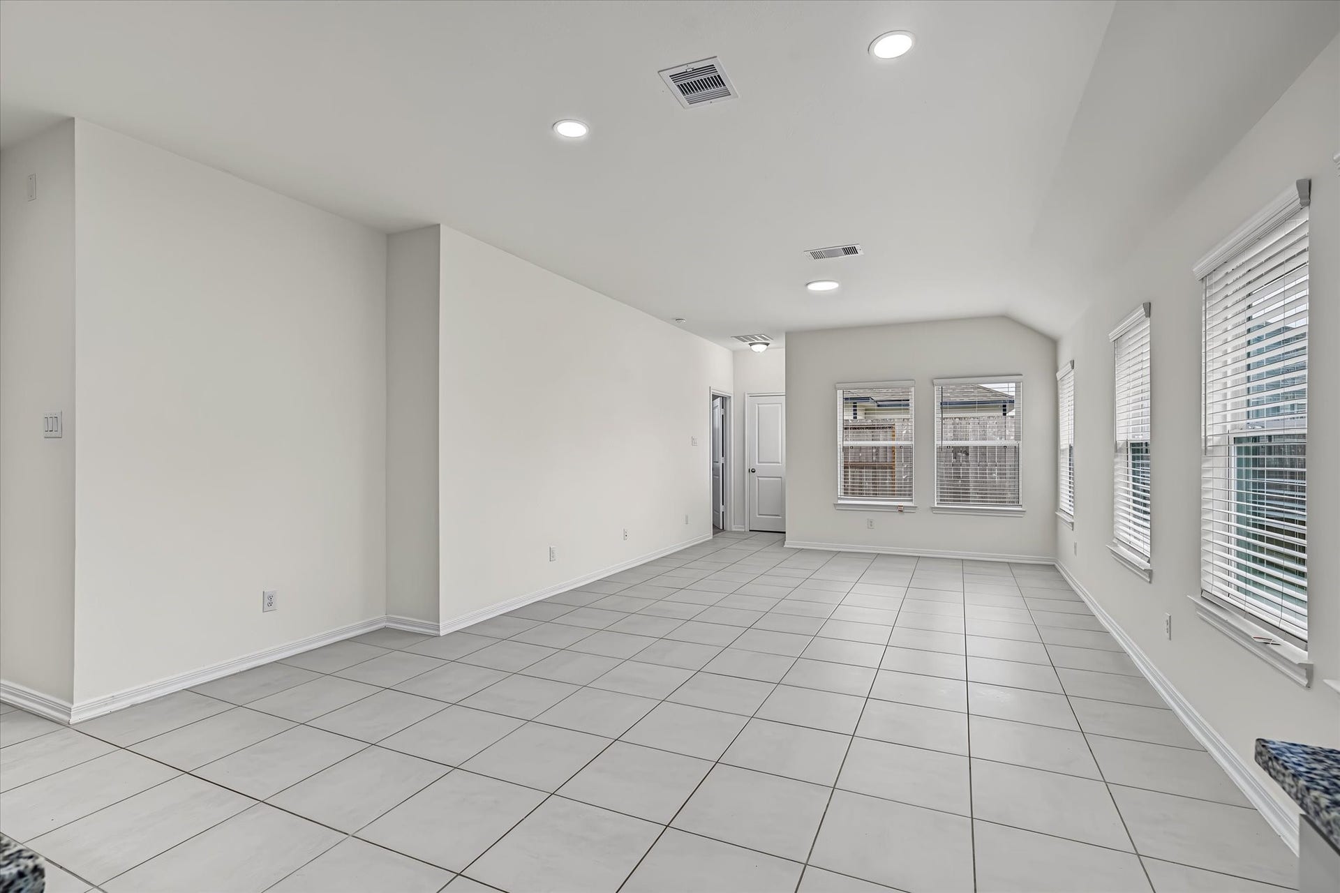 9607 Bright Song Lane, Houston, TX 77078 Spacious and bright open-concept living area with large windows and sleek tile flooring, perfect for modern living.