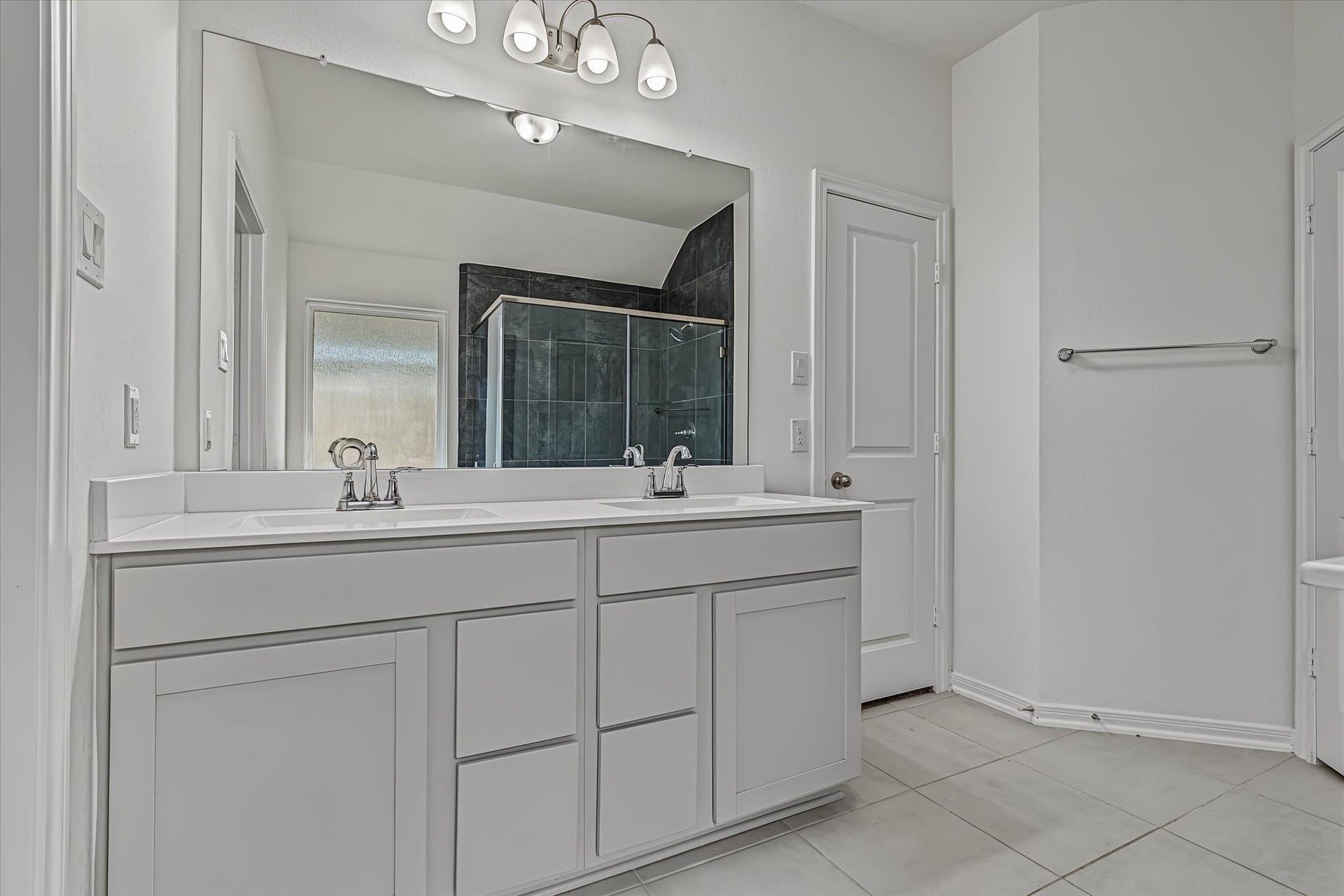9607 Bright Song Lane, Houston, TX 77078 Spacious Primary bathroom featuring a dual-sink vanity, elegant lighting, and a large mirror, complemented by a sleek glass-enclosed shower.