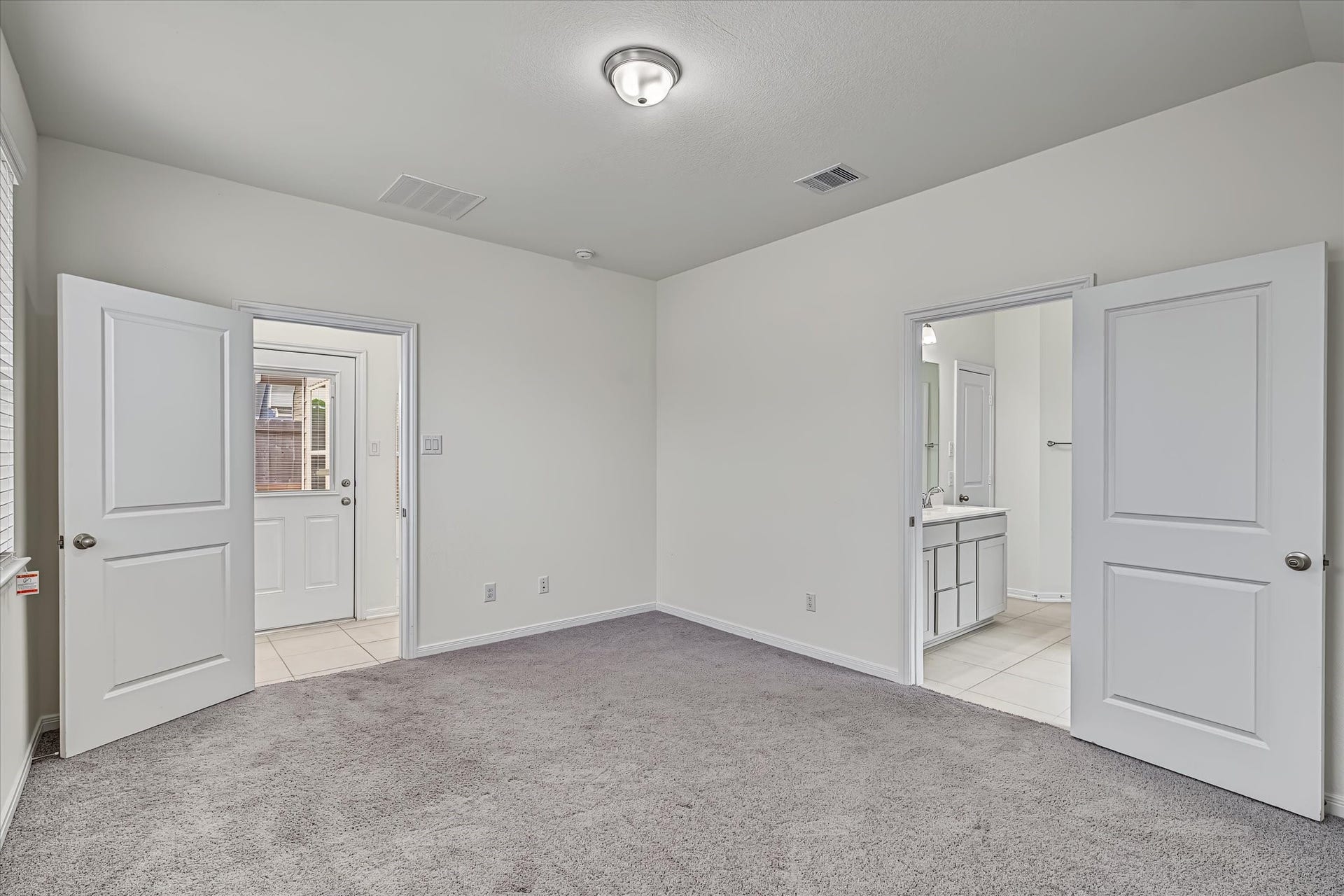 9607 Bright Song Lane, Houston, TX 77078 Spacious bedroom with soft carpeting, featuring two doorways leading to a bathroom and an additional room, offering convenient access and ample natural light.