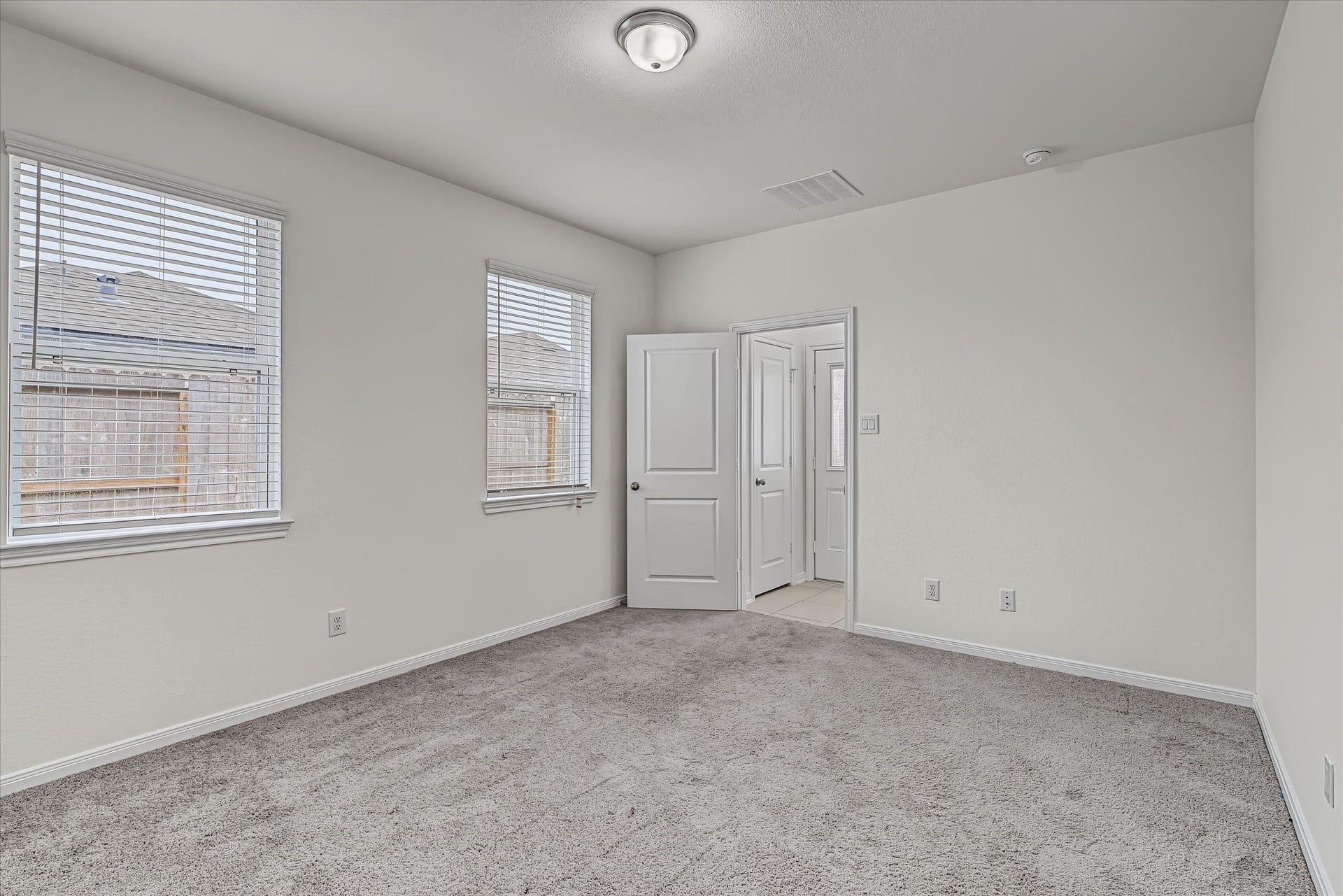 9607 Bright Song Lane, Houston, TX 77078 Bright and airy bedroom featuring plush carpet, neutral walls, and abundant natural light from two large windows.