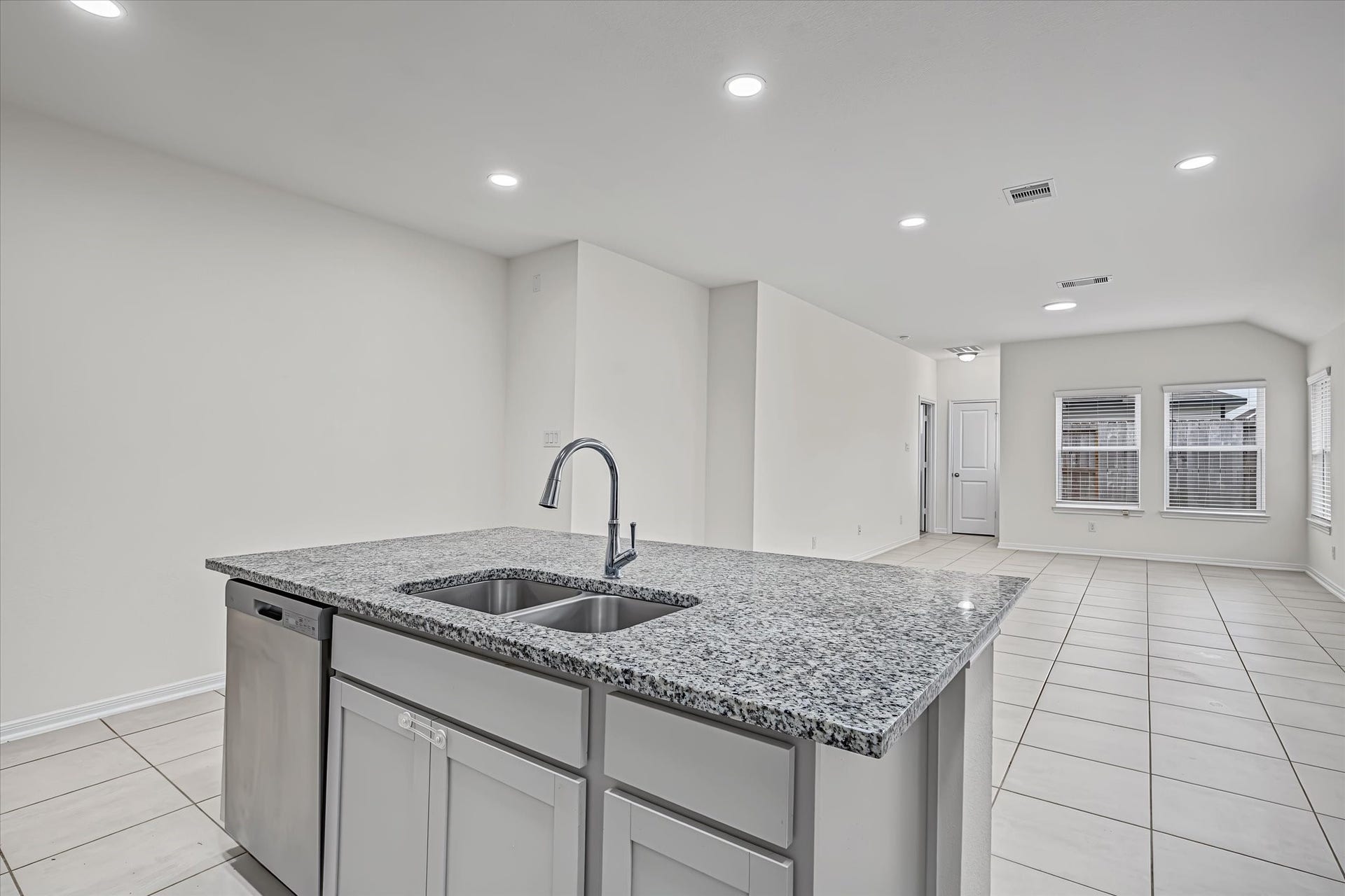 9607 Bright Song Lane, Houston, TX 77078 A modern kitchen with a sleek granite island, integrated sink, and ample natural light flowing into the spacious, open-plan living area.
