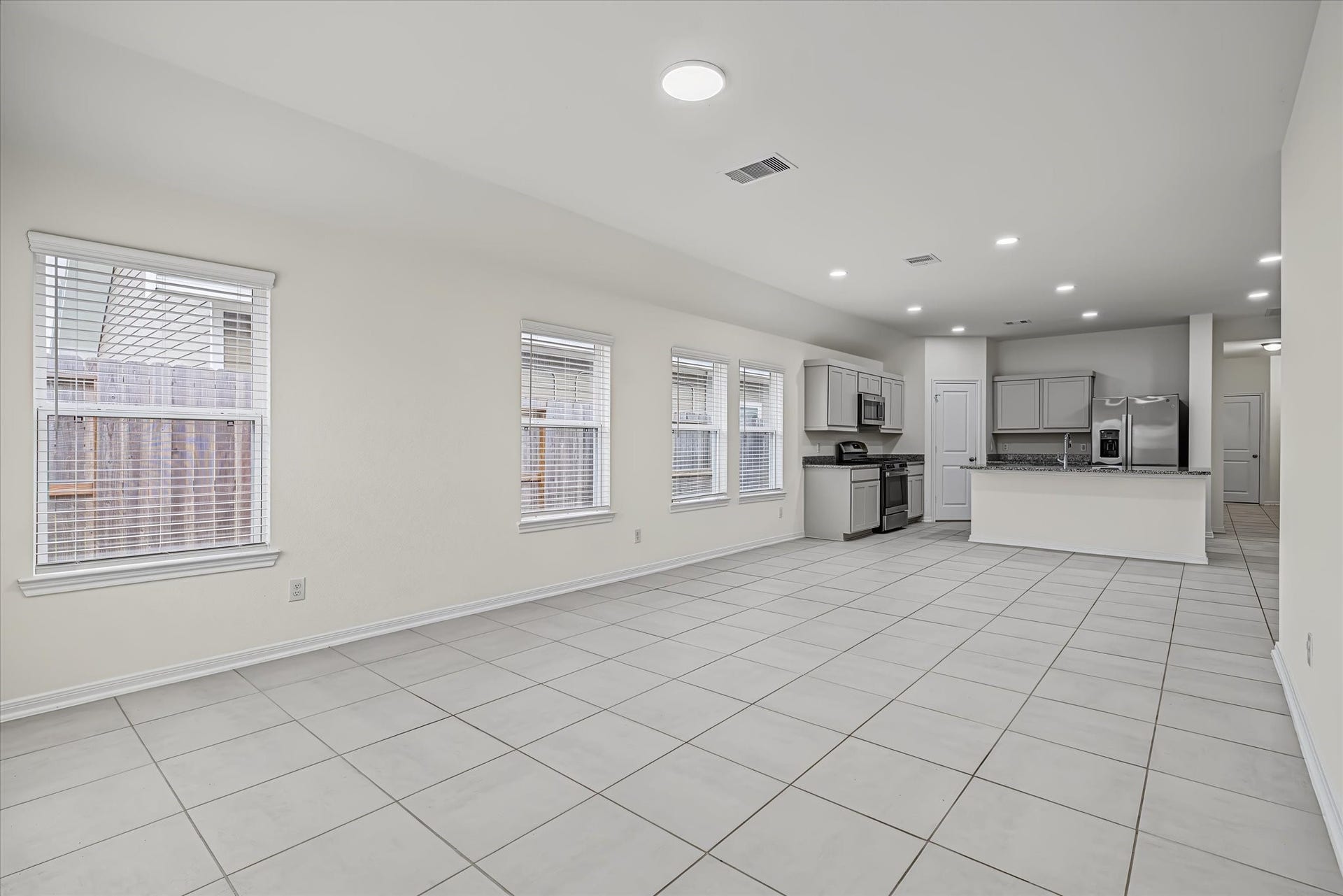 9607 Bright Song Lane, Houston, TX 77078 Spacious open-concept living area with large windows for natural light, modern kitchen with stainless steel appliances, and sleek tile flooring throughout.