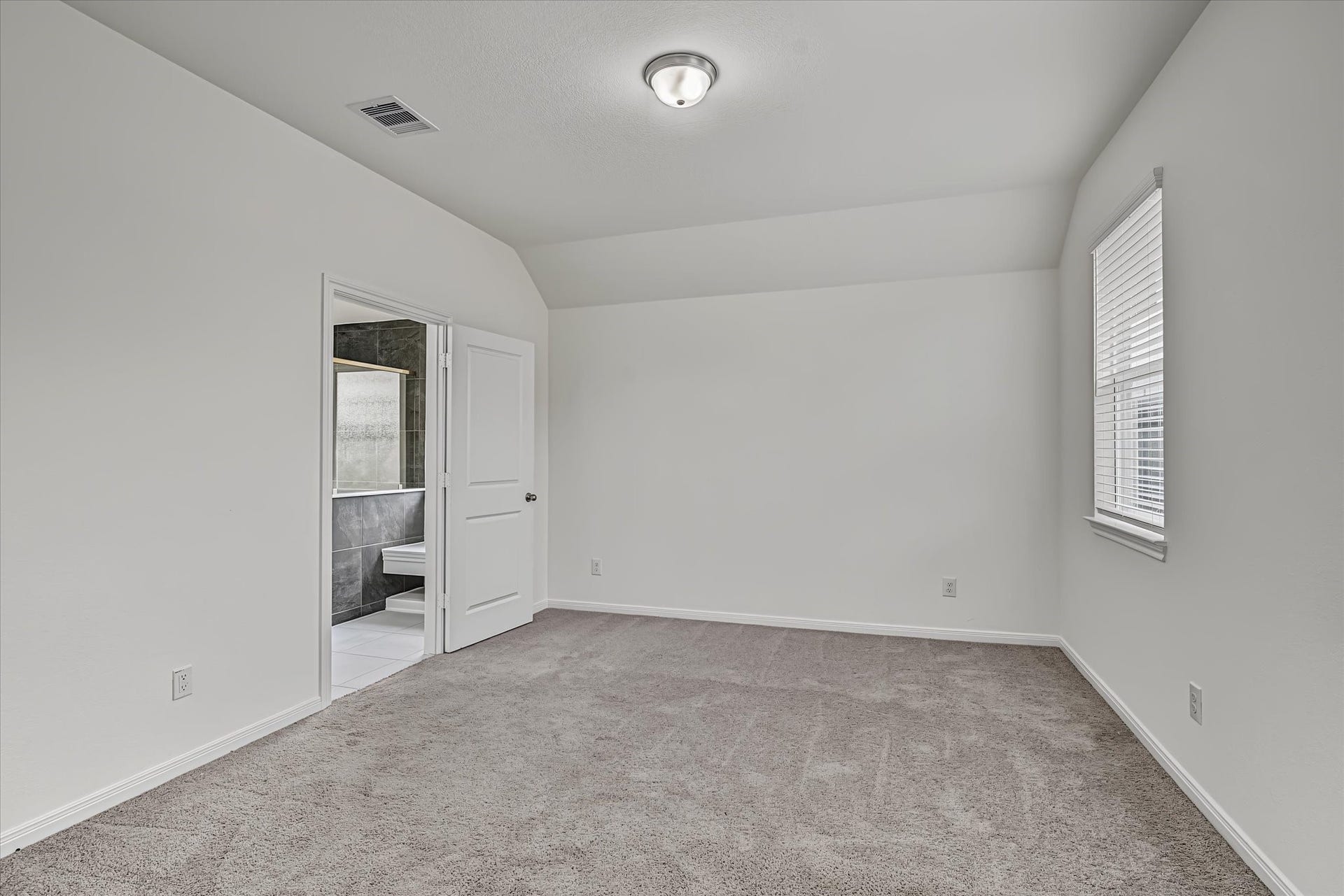 9607 Bright Song Lane, Houston, TX 77078 Spacious Primary bedroom with plush carpet, neutral walls, and ample natural light, featuring an en-suite bathroom for added convenience.