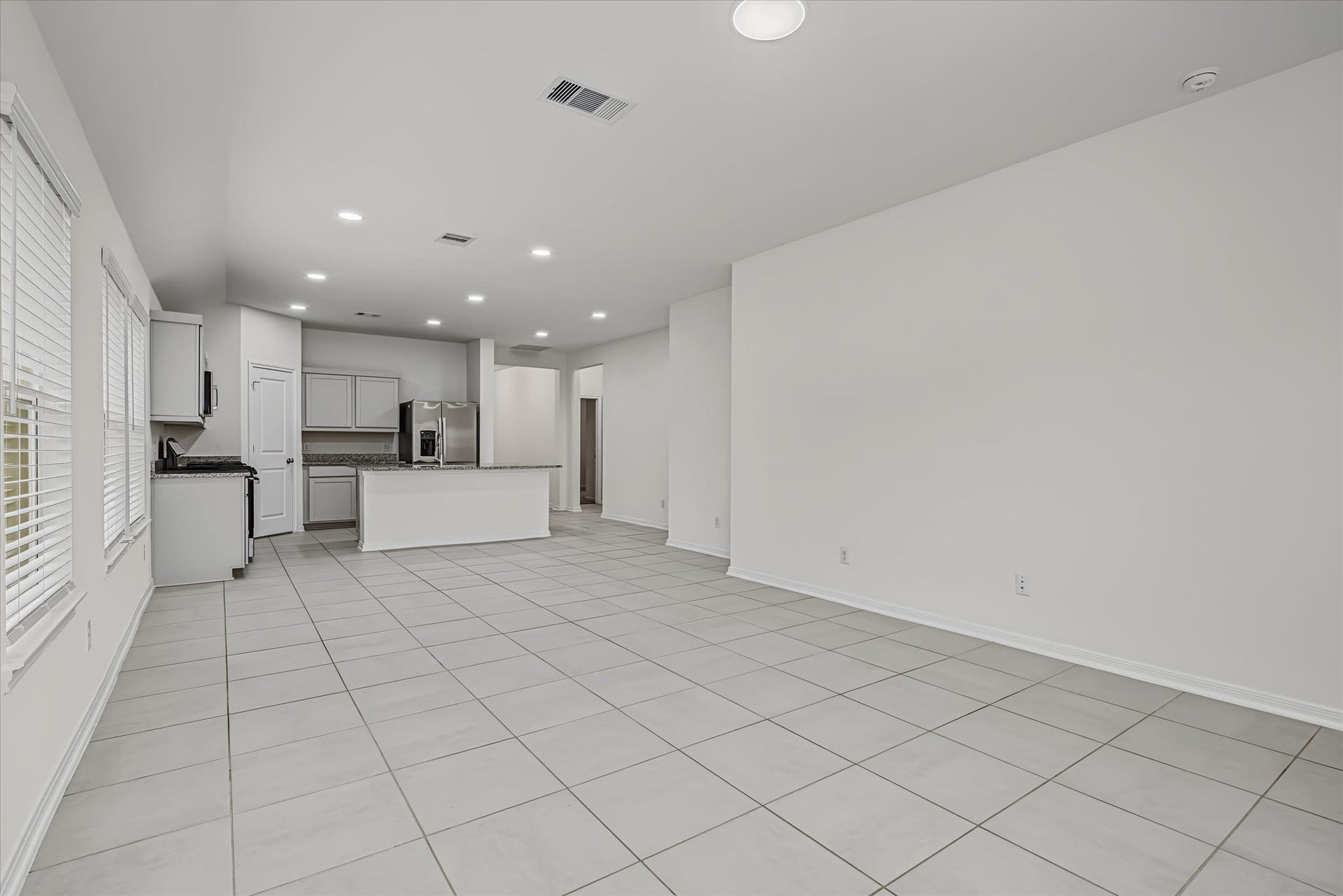 9607 Bright Song Lane, Houston, TX 77078 Open-concept living area with sleek tile flooring flows seamlessly into a modern kitchen featuring stainless steel appliances and a spacious island.