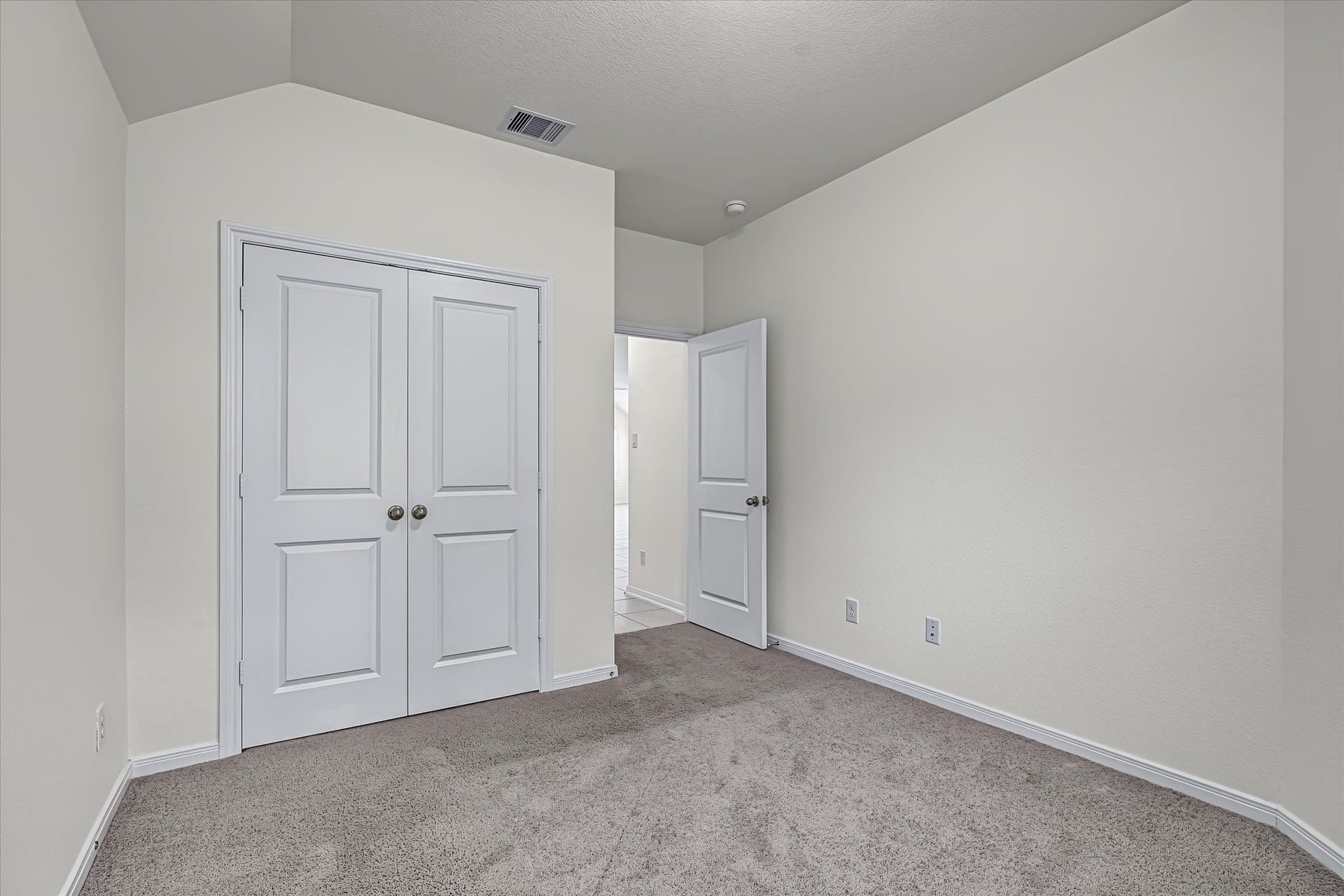 9607 Bright Song Lane, Houston, TX 77078 Bright and airy bedroom with plush carpeting and a spacious double-door closet, offering ample storage and a clean, neutral palette.