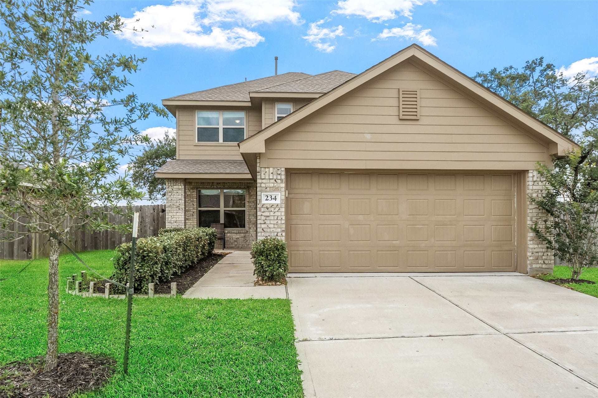 234 Bennett Loop, Angleton, TX 77515 This charming two-story house features a neutral-toned exterior with a combination of siding and brick.