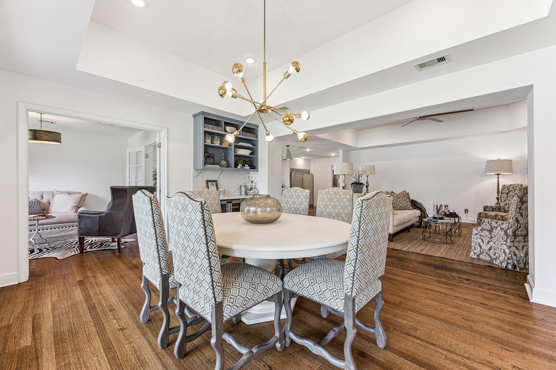 2503 Stoney Brook Drive, Houston, TX 77063 The formal dining room (15x12) is anchored by a
striking brass chandelier and warm hardwood floors beneath a tray ceiling. Abundant natural light fills the space through windows with blinds, creating a
bright and inviting setting for both everyday meals and formal gatherings. The adjacent dry bar adds a refined touch and convenient serving space, making the room especially well suited for entertaining.