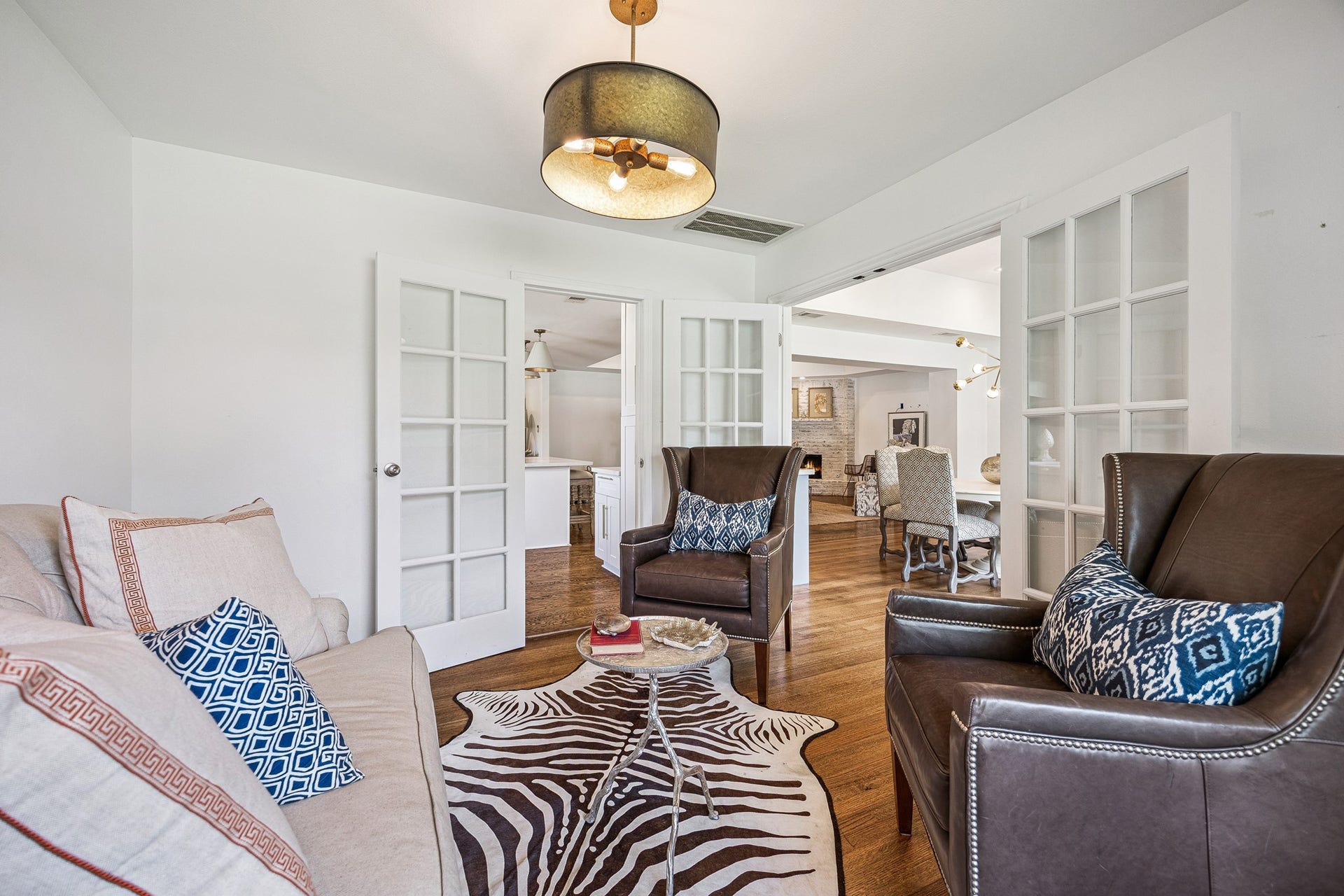 2503 Stoney Brook Drive, Houston, TX 77063 French doors open to a charming sitting room, offering a versatile space for a home office, reading retreat, or additional lounge area. Rich hardwood flooring and a decorative light fixture complete the inviting space.