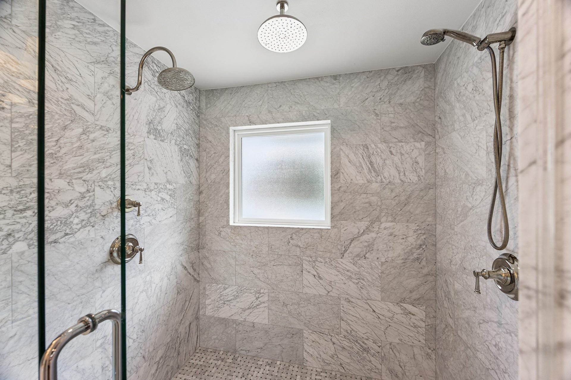 2503 Stoney Brook Drive, Houston, TX 77063 The beautifully updated primary bathroom features an oversized walk-in shower with marble-look tile and a frameless glass enclosure. Dual showerheads and a built-in bench create a luxurious, spa-inspired experience.