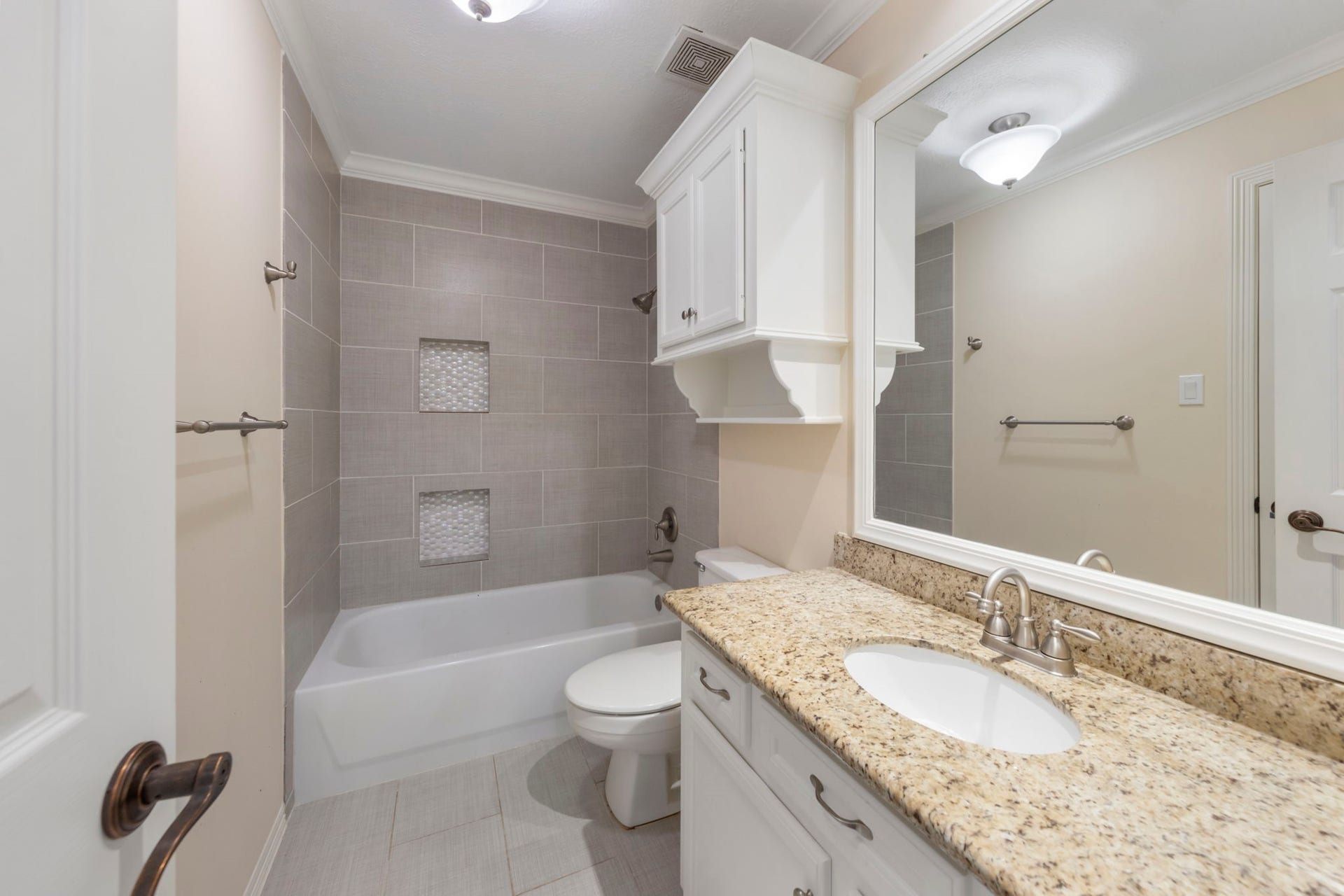 90 W Horizon Ridge Place, Spring, TX 77381 This bathroom, located at the top of the back stairs, offers ensuite access from the bedroom and hallway access for guests. It features updated tile, a tub/shower combo, and granite countertops.