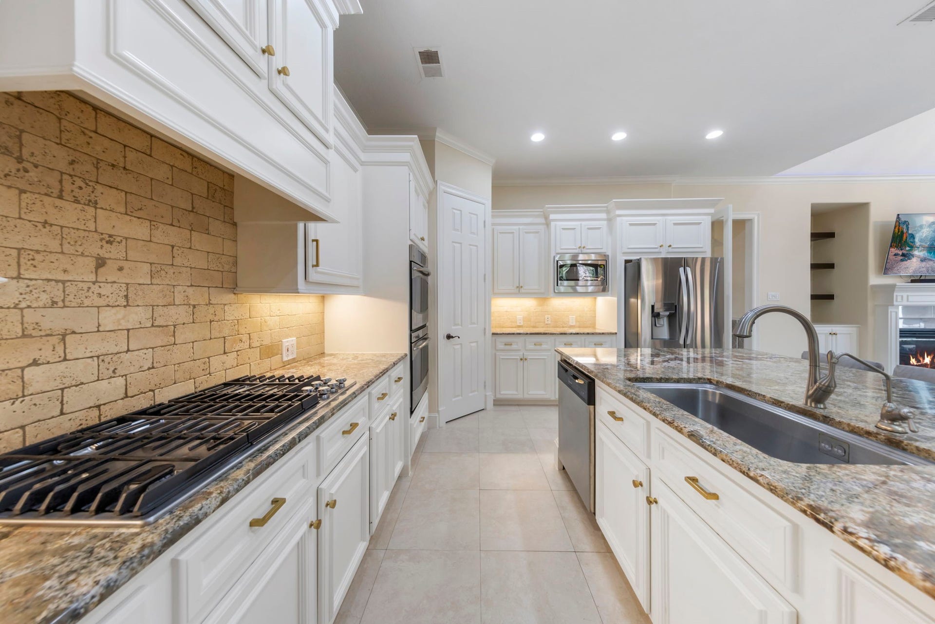 90 W Horizon Ridge Place, Spring, TX 77381 The chefs kitchen features a gas cooktop, stainless steel appliances, light cabinetry, and a large stainless steel sink set in a spacious island.
