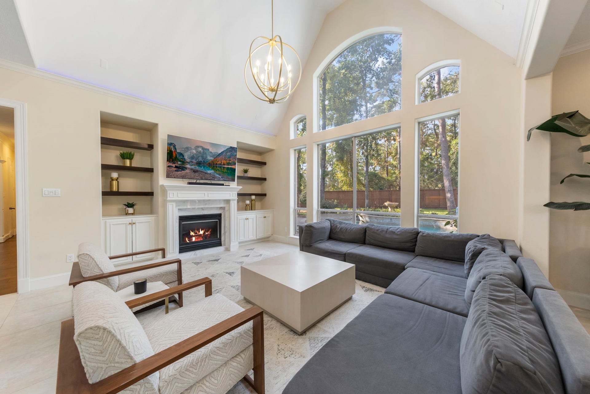 90 W Horizon Ridge Place, Spring, TX 77381 The family room boasts soaring ceilings, a large window with views of the backyard retreat, stylish pendant lighting, and built-ins that frame a cozy gas log fireplace.