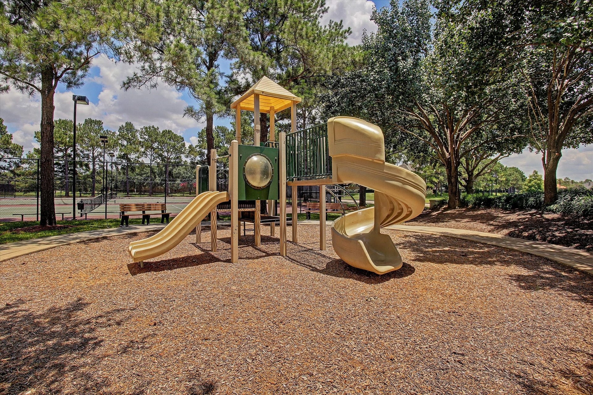 5310 Summerland Ridge Court, Houston, TX 77041 The neighborhood has plenty of playgrounds with slides and climbing structures, surrounded by trees and next to a tennis court, ideal for families and outdoor activities.