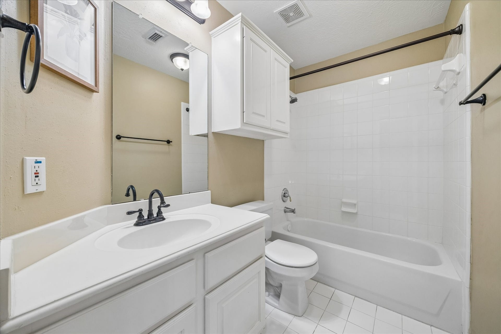 5310 Summerland Ridge Court, Houston, TX 77041 Modern bathroom with a clean white design, featuring a bathtub with a tiled surround, a sleek vanity with black fixtures, and ample cabinet space for storage.