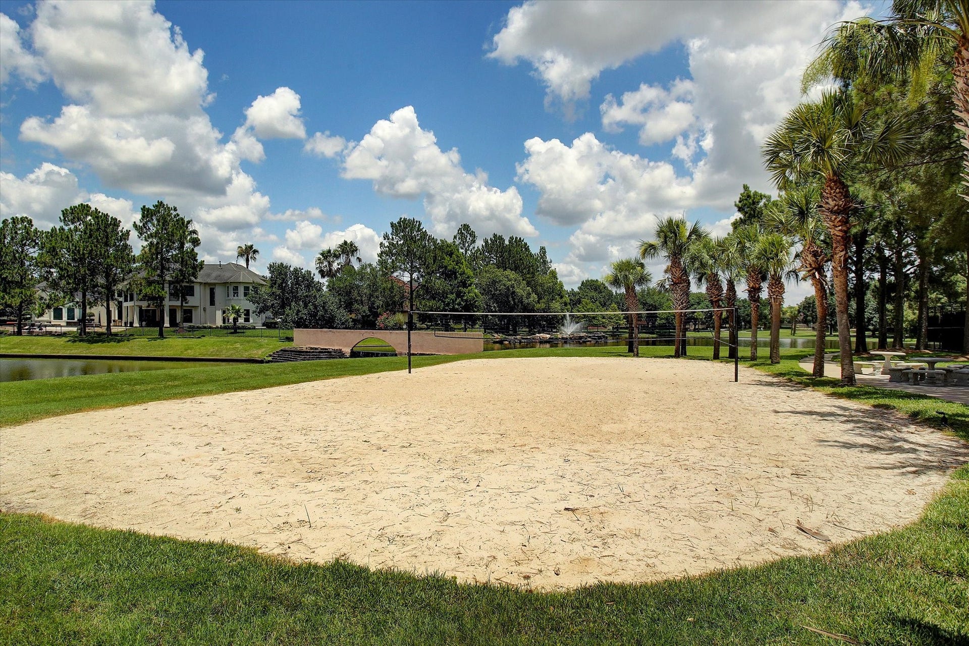 5310 Summerland Ridge Court, Houston, TX 77041 Lakes on Eldridge offers sand volleyball court set in a lush, landscaped area with palm trees and a pond nearby. Offering a scenic and recreational community environment.