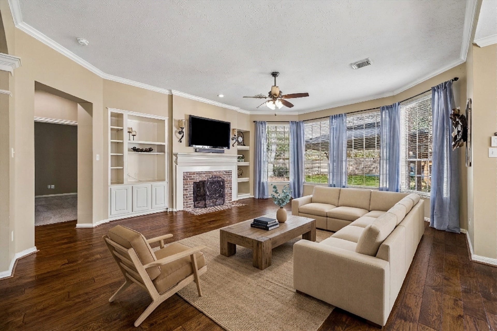 5310 Summerland Ridge Court, Houston, TX 77041 This spacious living room features elegant hardwood floors, a cozy brick fireplace, and built-in shelving. The room is enhanced by a ceiling fan and ample natural light from large windows. It offers an open view to the kitchen and a staircase, creating an inviting and connected living space.
This is a digitally staged image.
