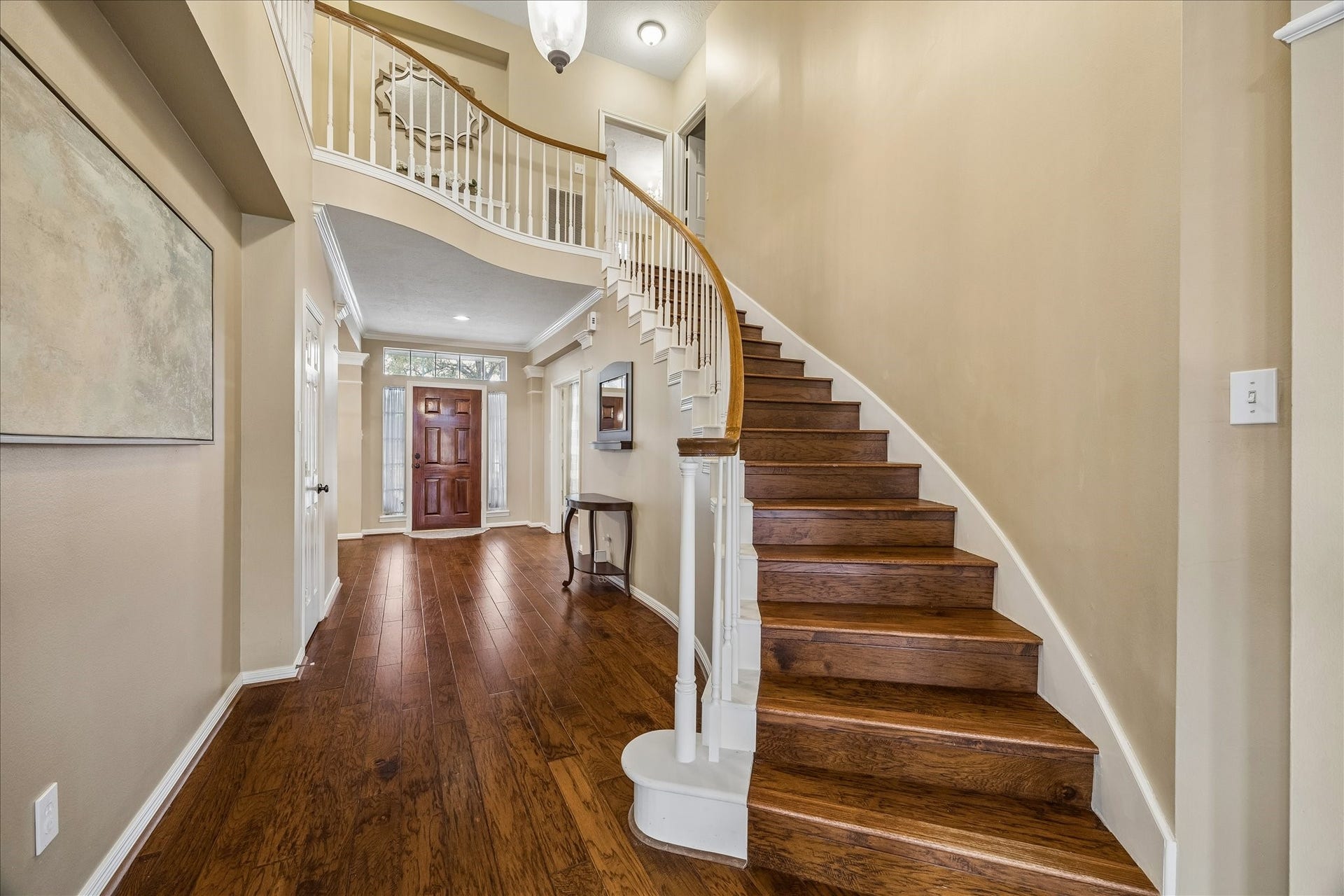 5310 Summerland Ridge Court, Houston, TX 77041 This home offers a welcoming entryway with elegant hardwood flooring and a stunning curved staircase. The high ceiling and neutral walls enhance the spacious feel, while the wooden front door with glass side panels adds a touch of sophistication.