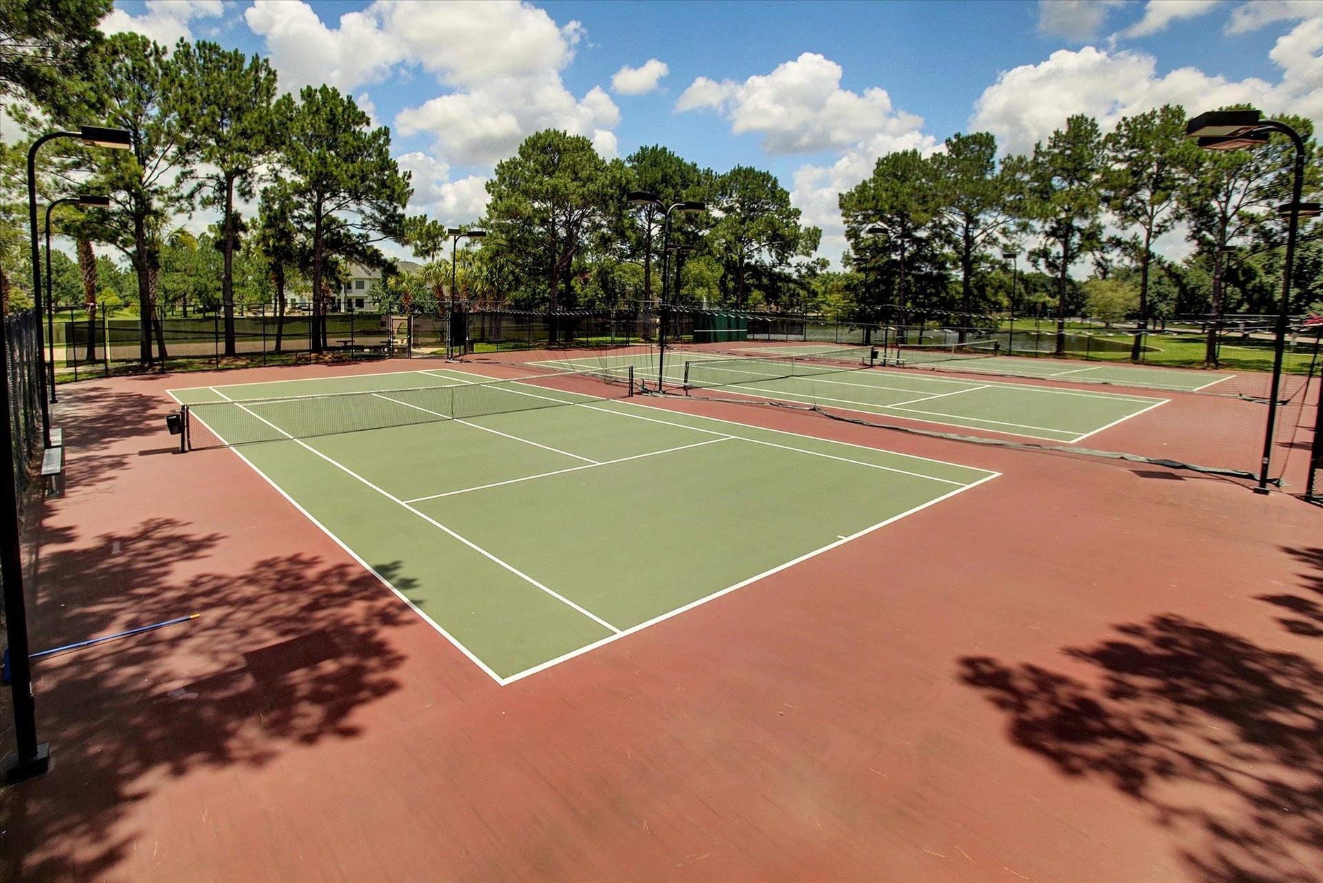 5310 Summerland Ridge Court, Houston, TX 77041 Lakes on Eldridge offers outdoor tennis court area surrounded by lush greenery and trees, offering a great recreational space for residents.