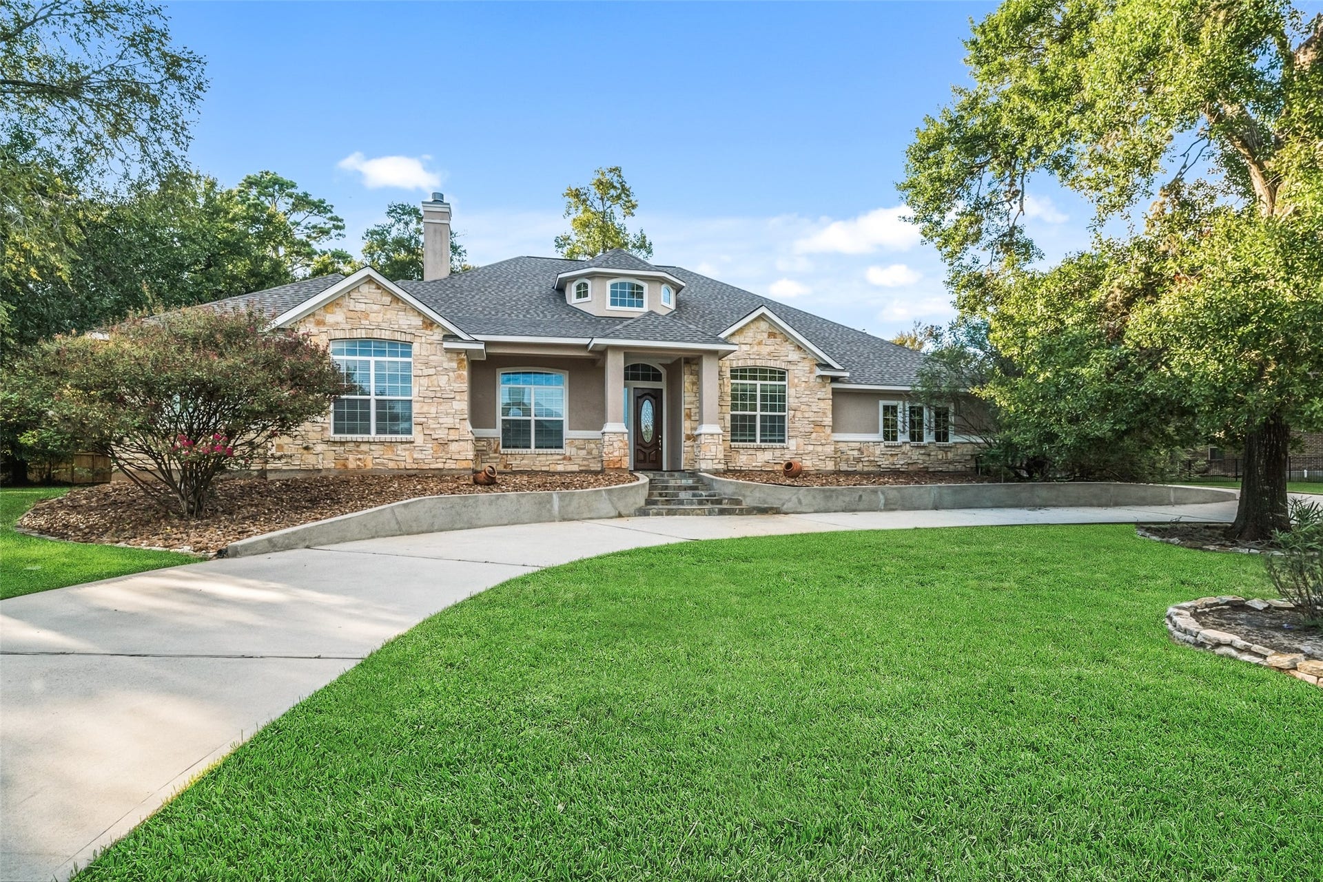 12195 N Lake Vista Drive, Willis, TX 77318 Experience elegance and convenience with this charming home featuring a spacious circle driveway, perfectly framed by lush greenery and a stunning stone exterior.