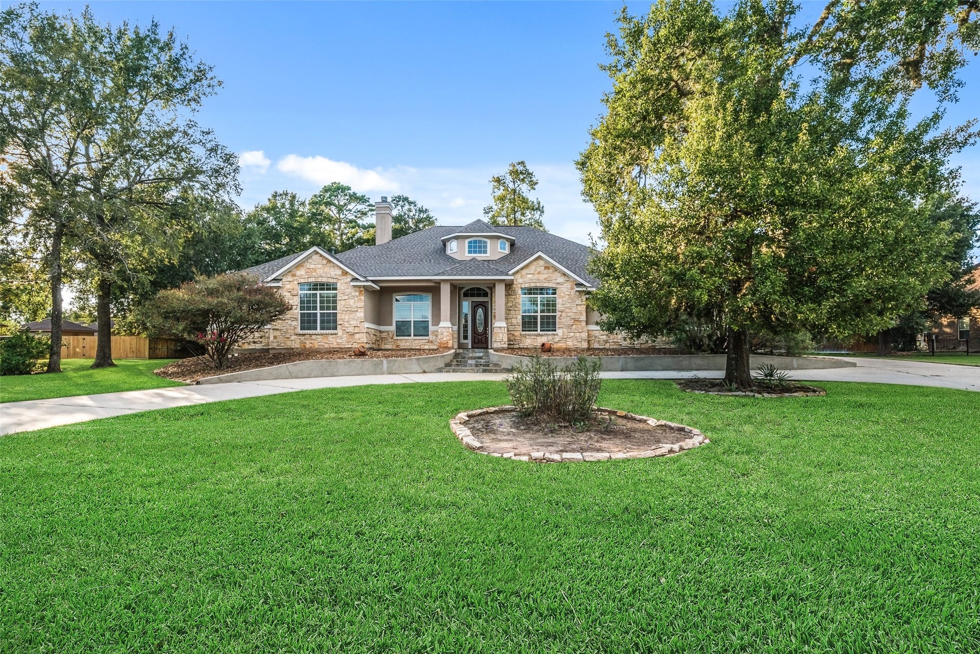 12195 N Lake Vista Drive, Willis, TX 77318 Nestled amidst lush greenery, this charming stone-front home exudes warmth and elegance, offering a picturesque street view with its welcoming circular driveway and beautifully landscaped front yard.