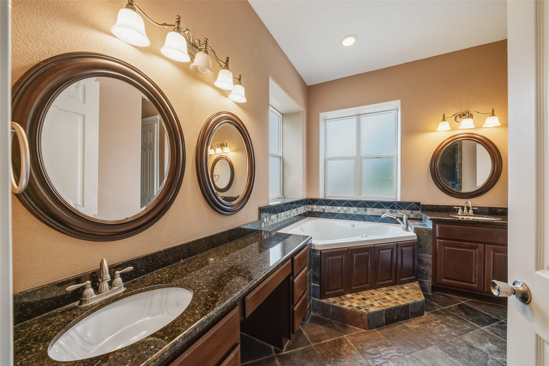 12195 N Lake Vista Drive, Willis, TX 77318 Spacious kitchen with elegant dark wood cabinetry, sleek granite countertops, and modern stainless steel appliances, highlighted by a central island and abundant natural light from large windows.