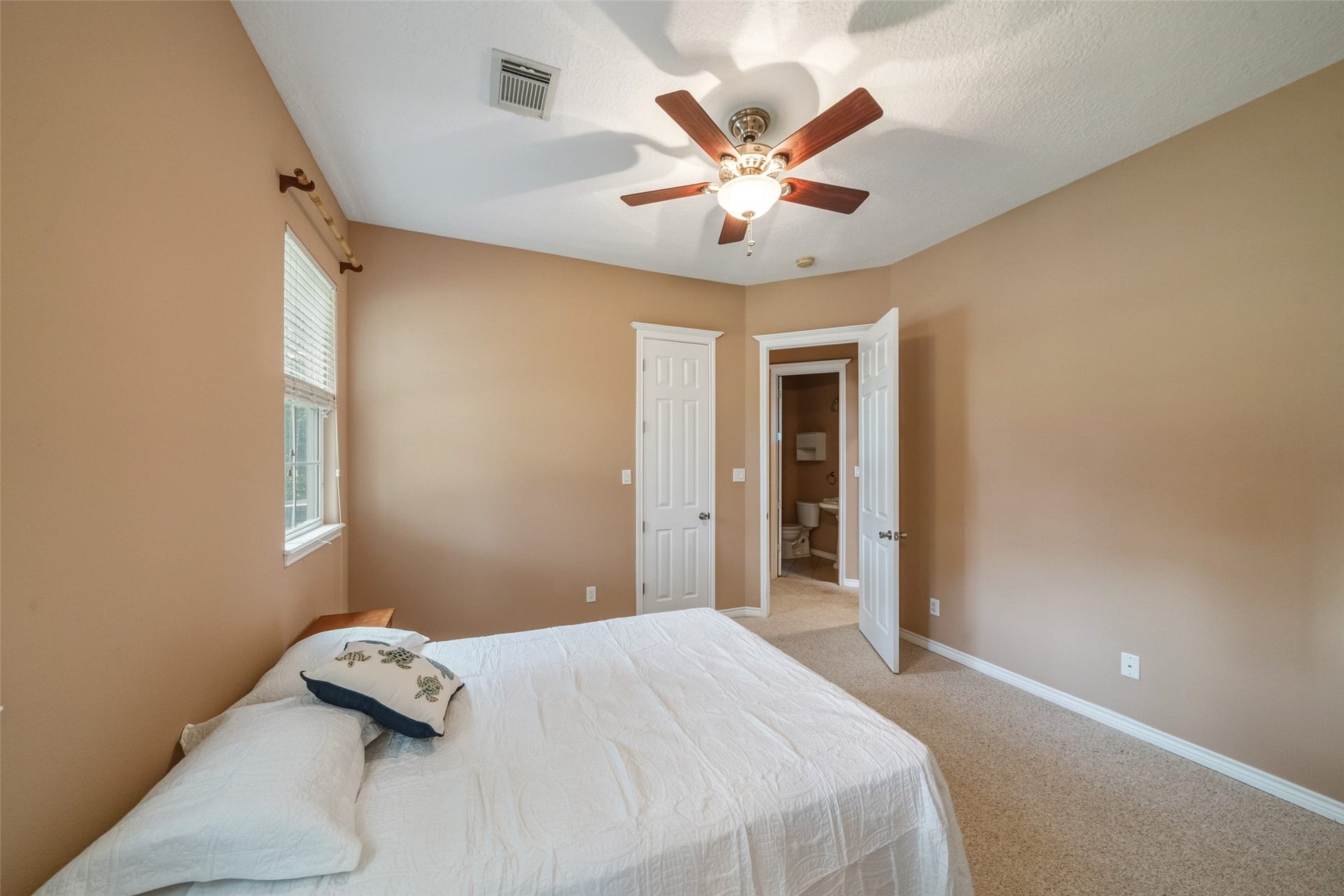 12195 N Lake Vista Drive, Willis, TX 77318 Spacious bedroom with a vaulted ceiling, featuring a ceiling fan and neutral tones. It includes an en-suite bathroom with a luxurious bathtub, adding comfort and convenience.