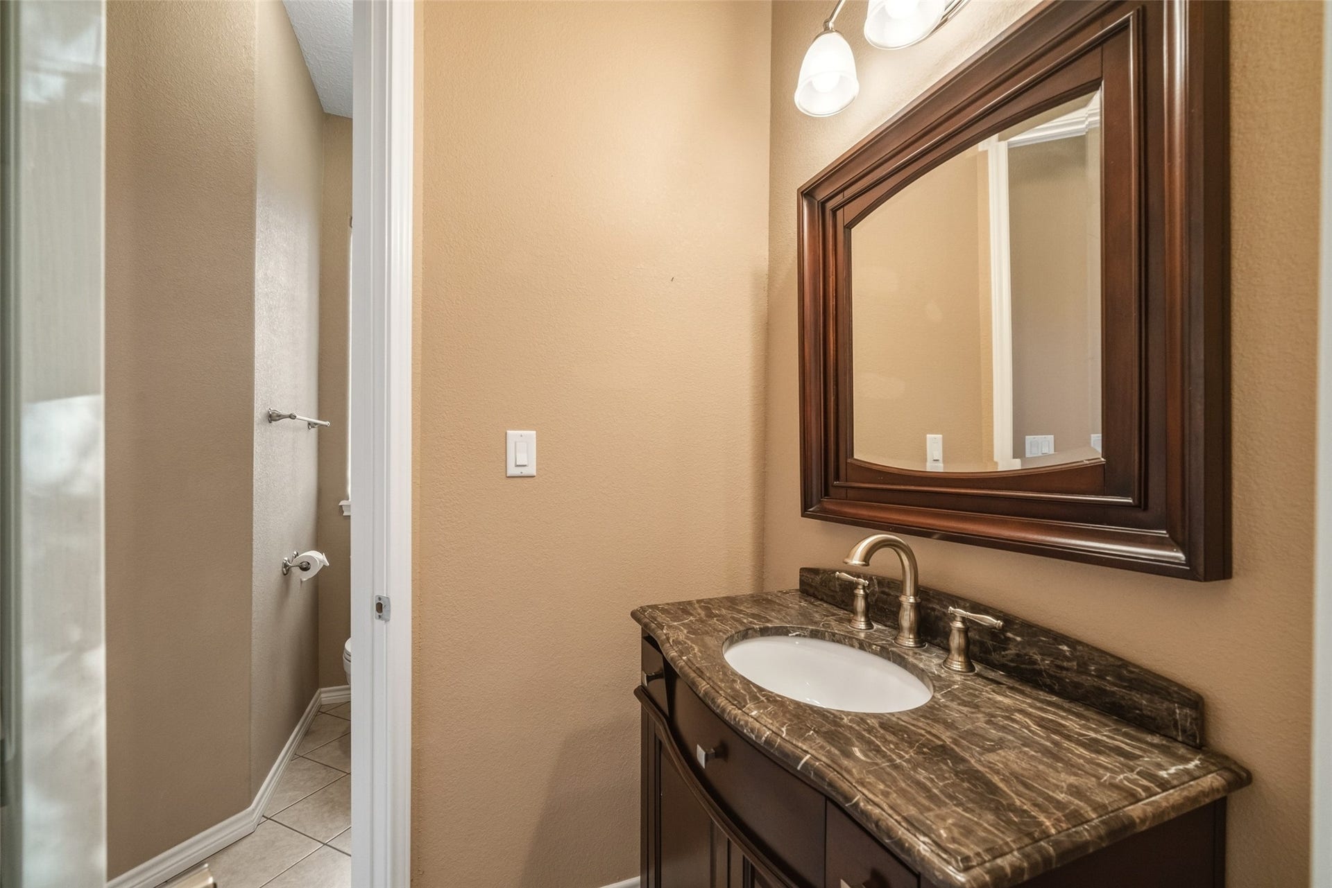 12195 N Lake Vista Drive, Willis, TX 77318 Luxurious bathroom featuring dual vanities with elegant dark granite countertops, a spacious corner soaking tub, and stylish tile flooring, all illuminated by warm, inviting light fixtures.
