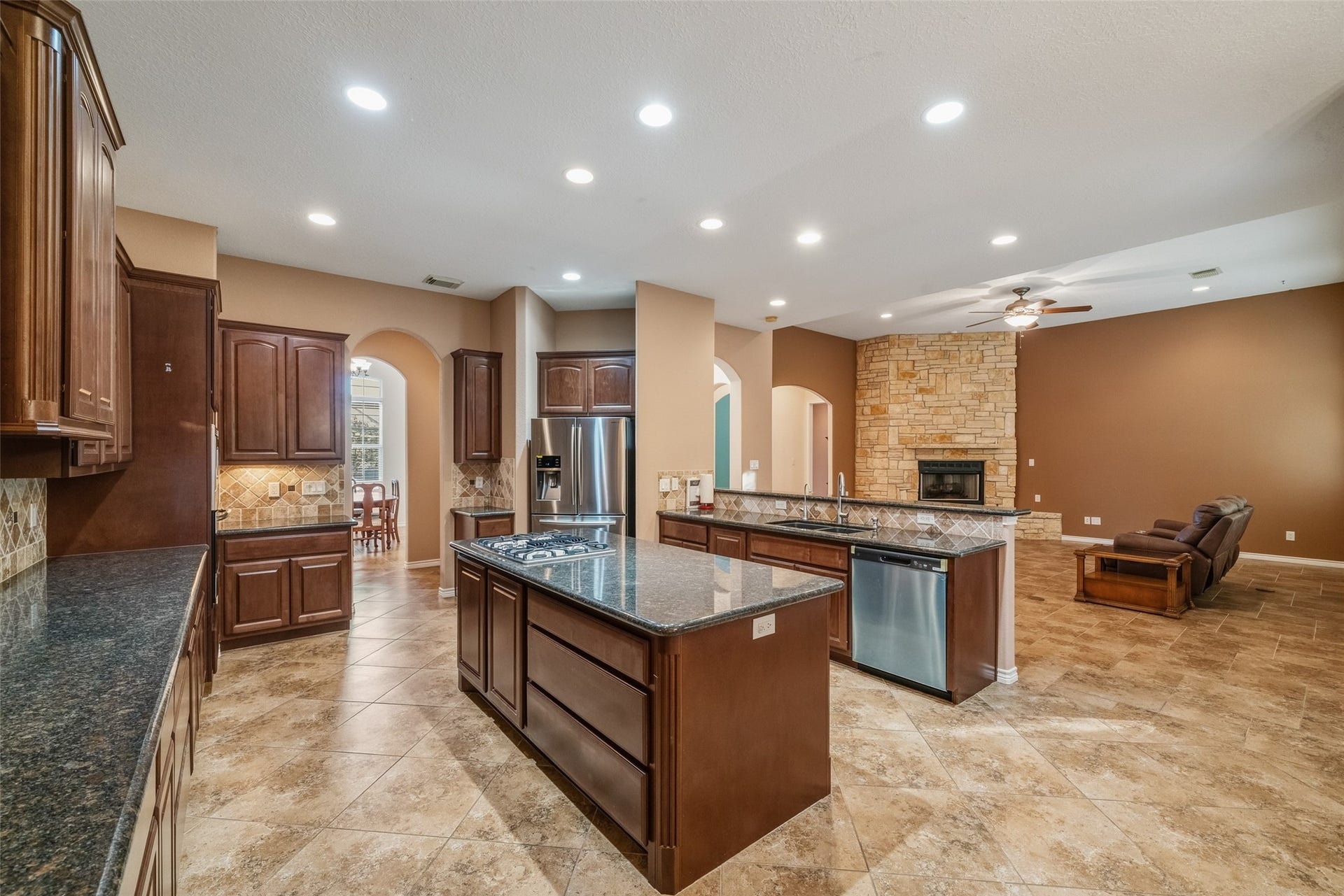 12195 N Lake Vista Drive, Willis, TX 77318 Spacious living room featuring a stunning stone fireplace, elegant tile flooring, and abundant natural light from large windows and a glass door leading to the outdoor area.