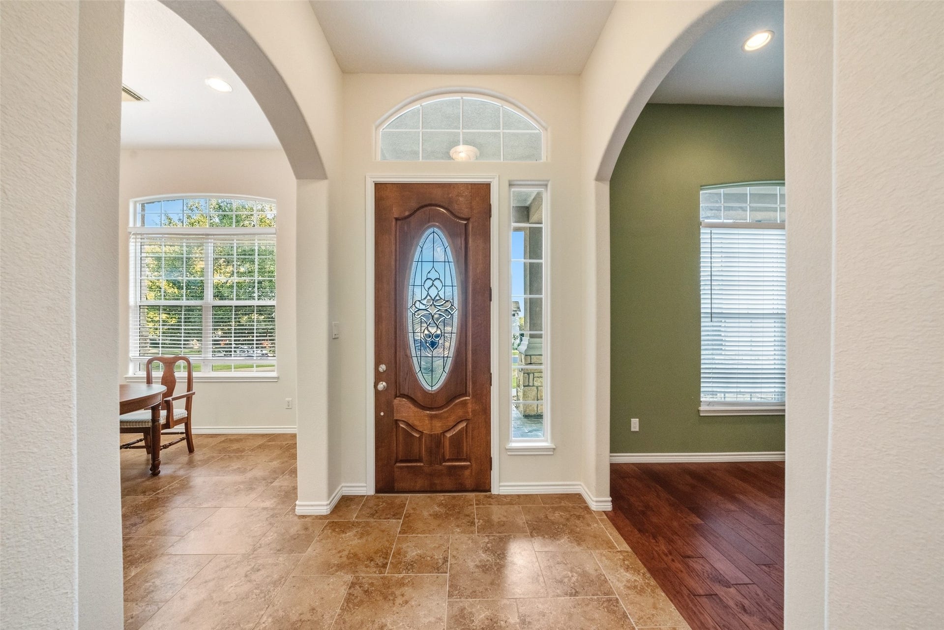 12195 N Lake Vista Drive, Willis, TX 77318 Step into elegance through a grand entryway featuring a beautifully crafted wooden door, framed by arched openings and abundant natural light streaming through large windows, setting a warm and inviting tone.