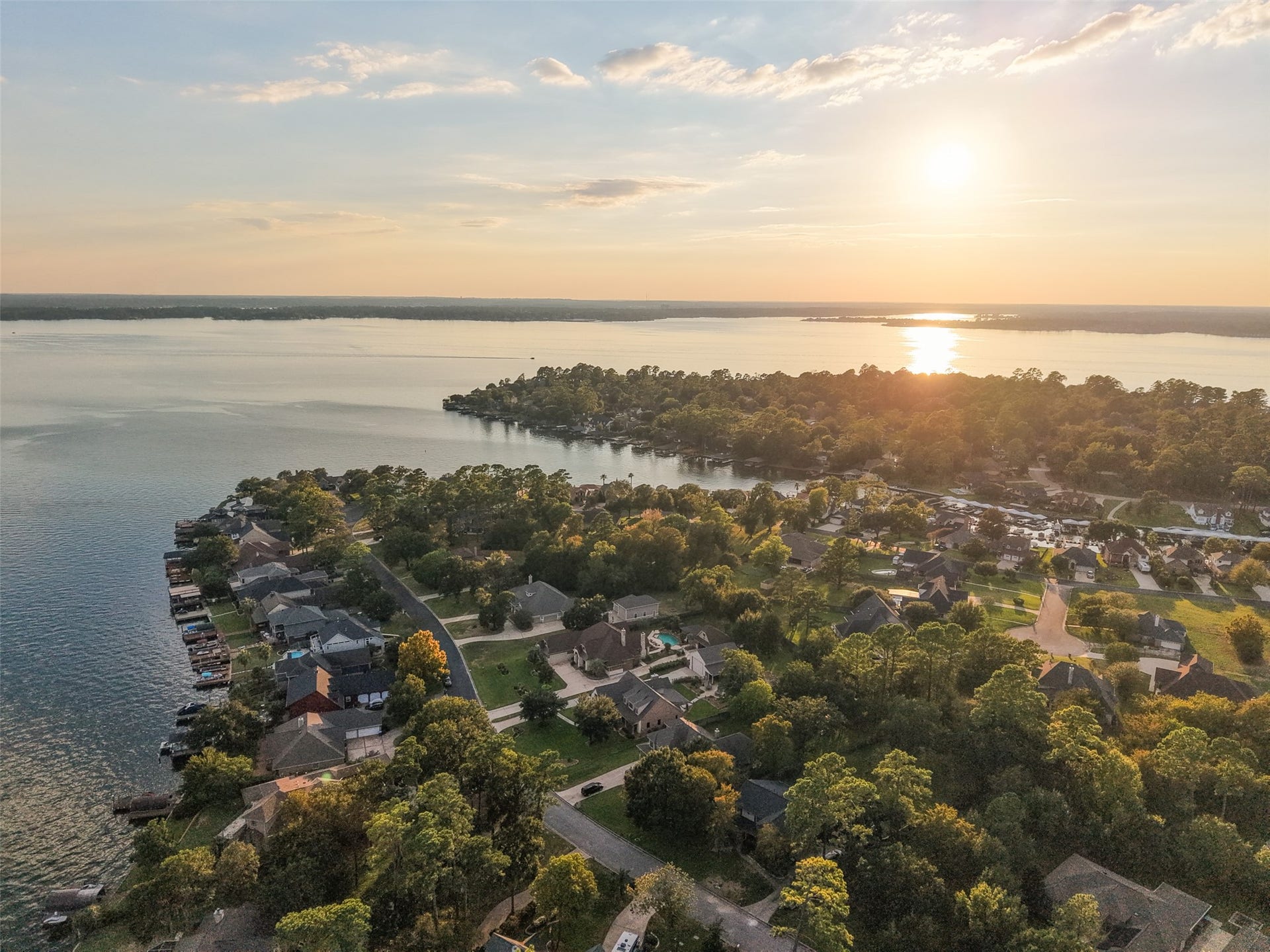 12195 N Lake Vista Drive, Willis, TX 77318 Enjoy breathtaking sunsets over the expansive lake, with charming homes nestled along the shoreline in a serene, picturesque neighborhood.