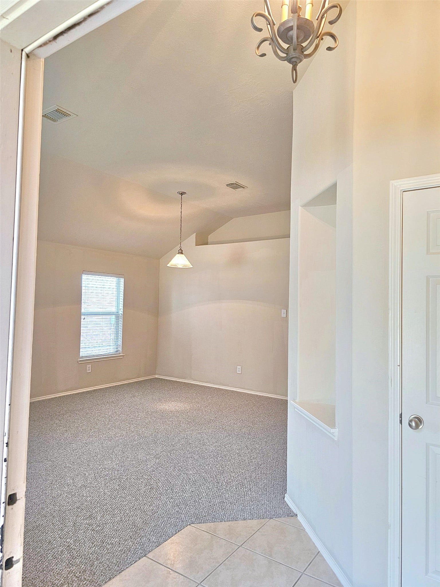 18234 Eton Ridge Court, Richmond, TX 77407 Bright and spacious room with vaulted ceilings, soft carpeting, and elegant lighting, creating a welcoming atmosphere.