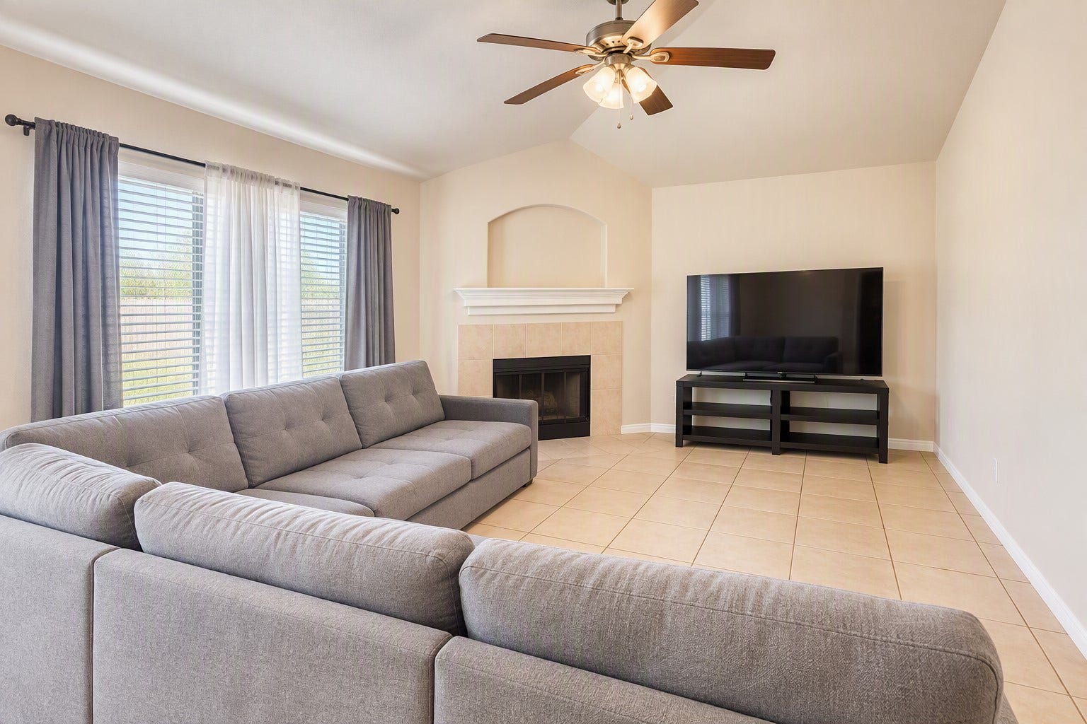 18234 Eton Ridge Court, Richmond, TX 77407 Spacious living room with a cozy fireplace, large sectional sofa, and high ceilings, perfect for relaxing or entertaining.
