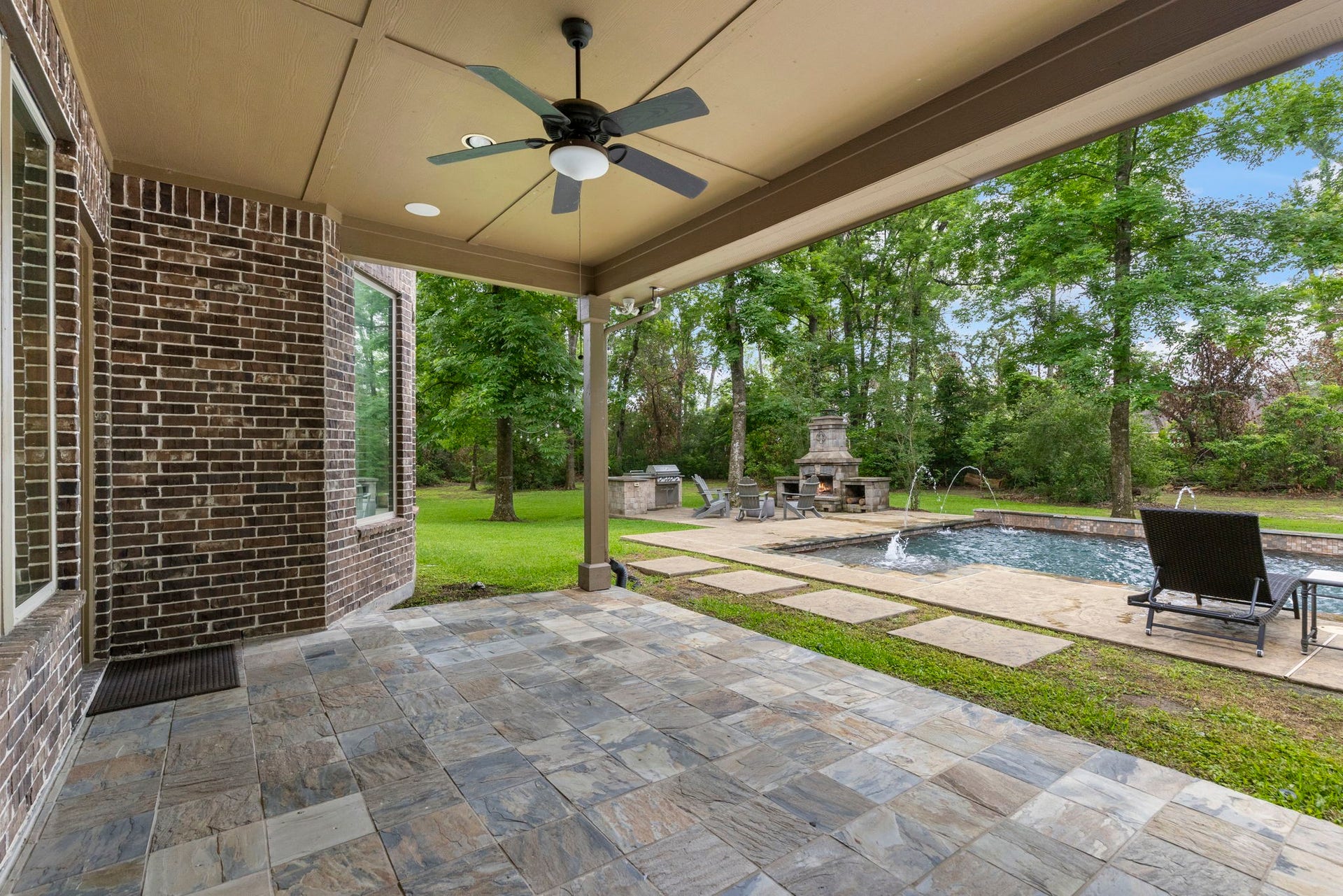 27015 Hidden Grove Landing Drive, Spring, TX 77386 Enjoy peaceful backyard views from the covered patio featuring slate tile flooring, ceiling fan, outdoor speakers, and a gas connection for future outdoor living enhancements.