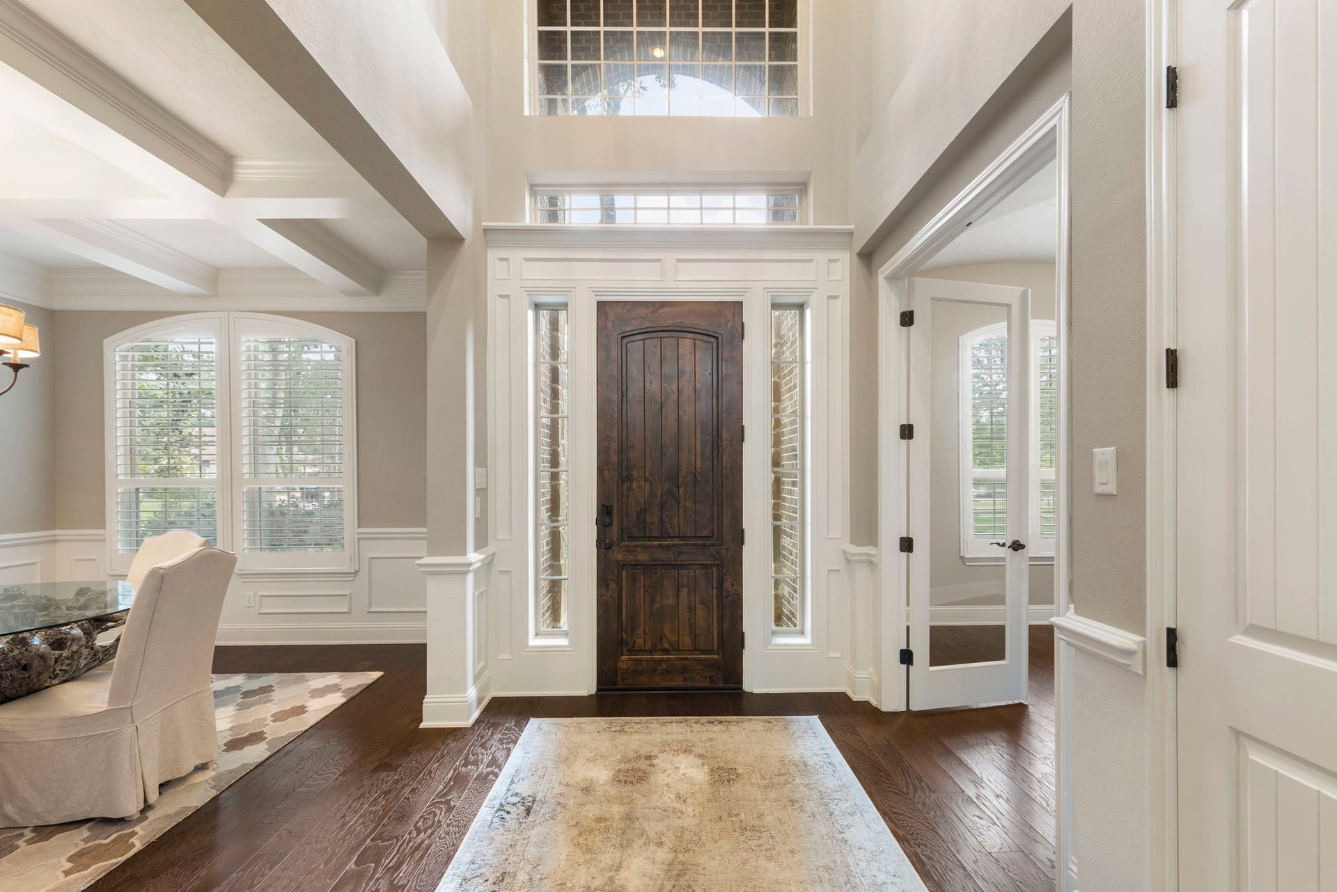 27015 Hidden Grove Landing Drive, Spring, TX 77386 Grand two-story Foyer featuring a solid wood front door with sidelights and transom window, detailed millwork, wood flooring, and elegant lower wall paneling.