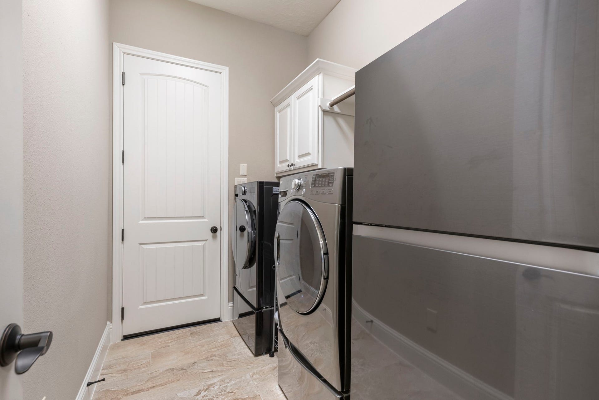 27015 Hidden Grove Landing Drive, Spring, TX 77386 Functional Utility Room with tile flooring, upper storage cabinetry, clothes drying rod, space for an additional refrigerator, and direct access to the garage.