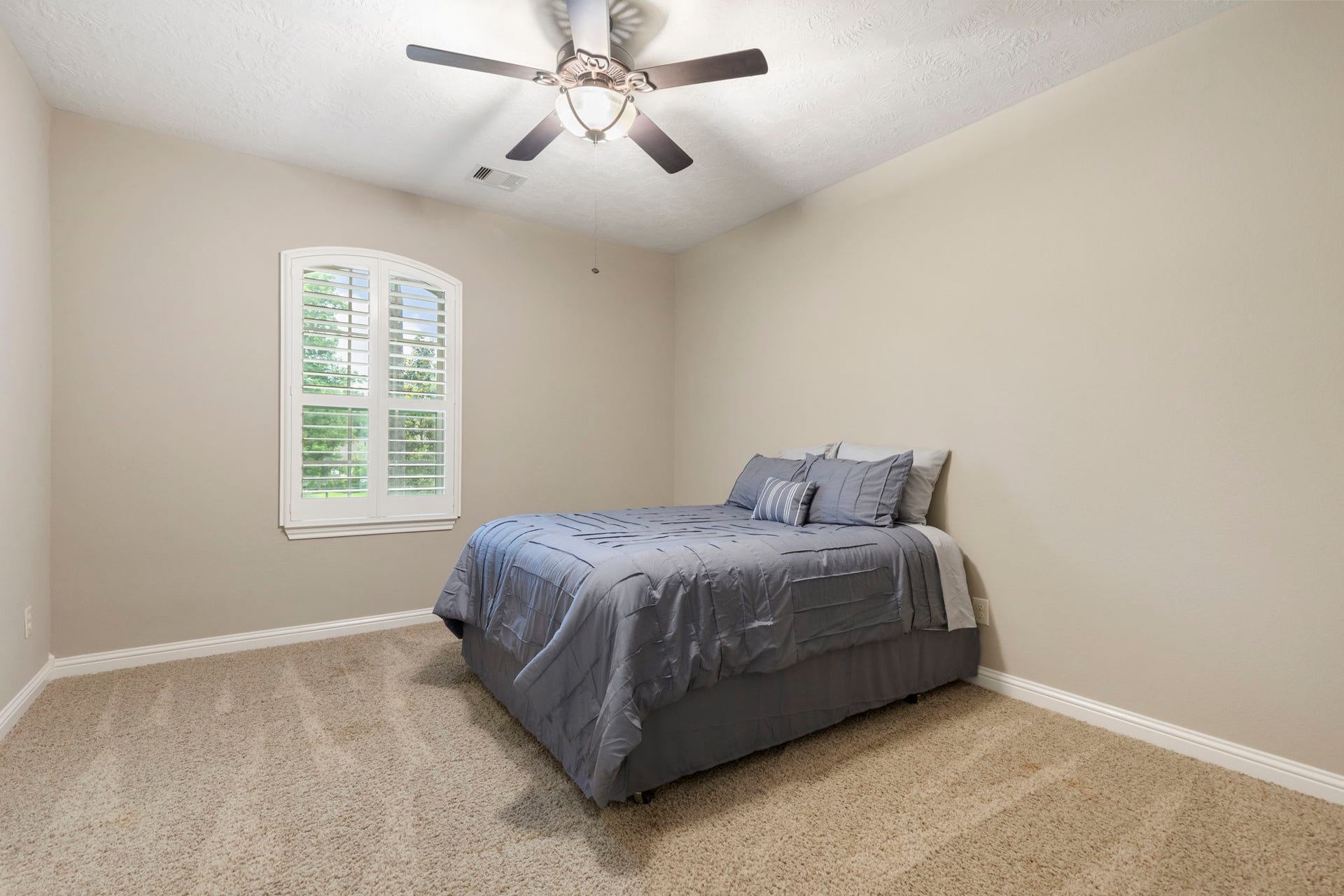 27015 Hidden Grove Landing Drive, Spring, TX 77386 Spacious upstairs Bedroom with carpeted flooring, ceiling fan, walk-in closet, and arched window with plantation shutters.