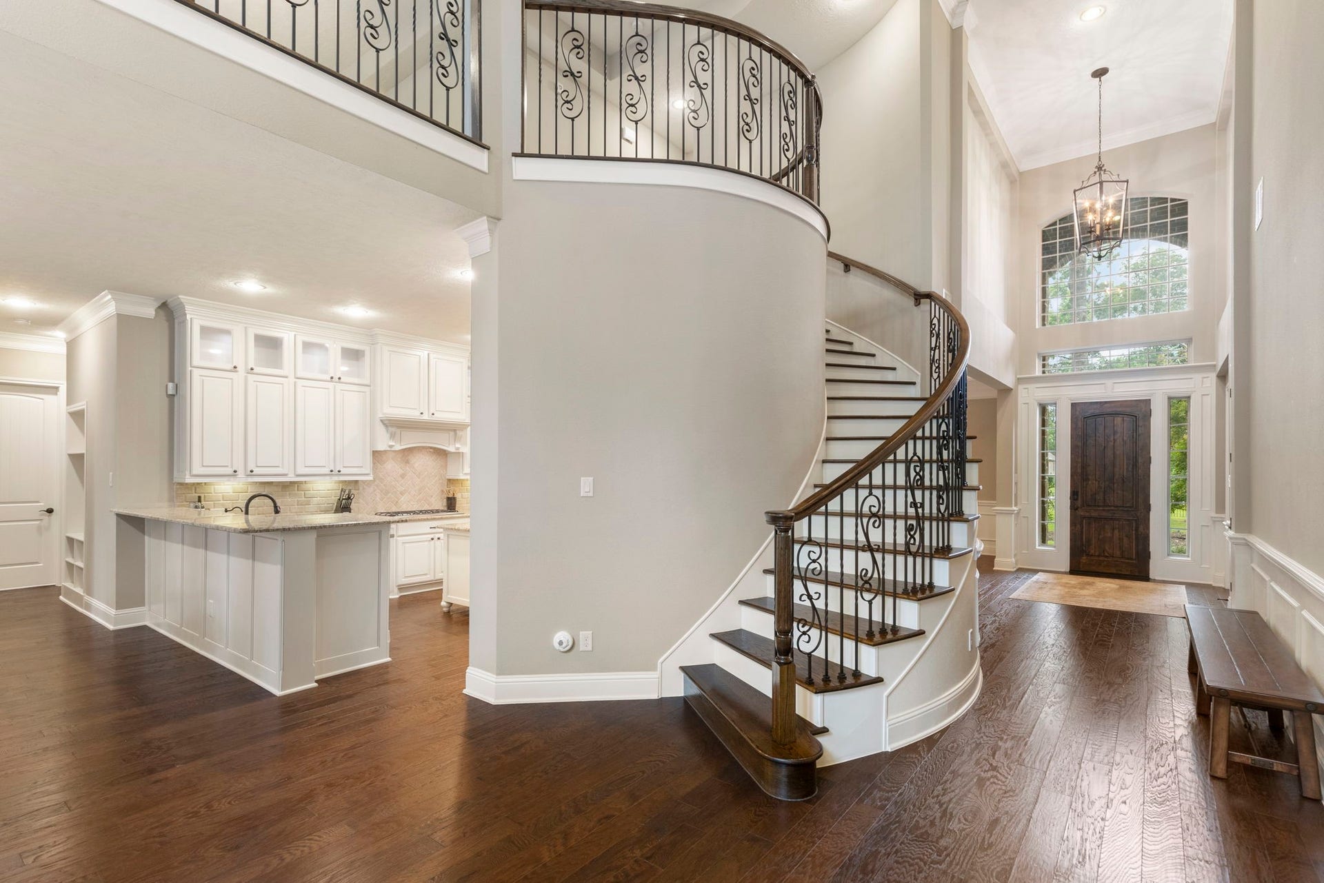 27015 Hidden Grove Landing Drive, Spring, TX 77386 Curved staircase with wood treads and wrought iron spindles creates a beautiful architectural focal point overlooking the main living area.