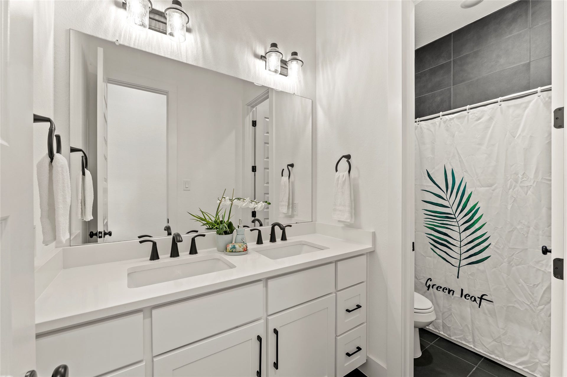 1934 Pleasant Grove Drive, Missouri City, TX 77459 This sleek and modern full bathroom features a crisp white double vanity with an expansive mirror, offering plenty of space for guests or family.
