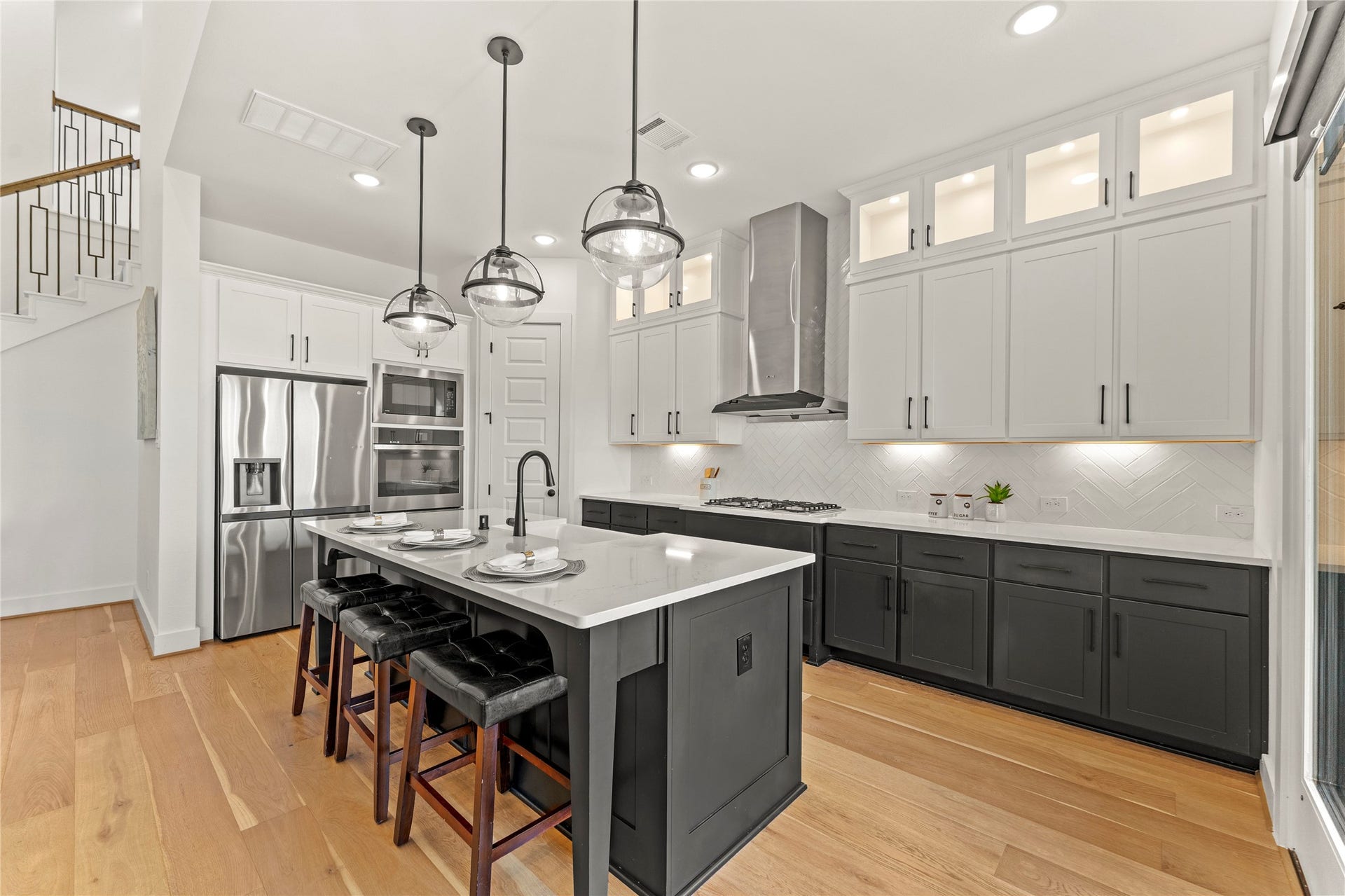 1934 Pleasant Grove Drive, Missouri City, TX 77459 Elegant white upper cabinets reach toward the ceiling with glass-front displays and under-cabinet lighting that beautifully illuminates the modern chevron-patterned backsplash.