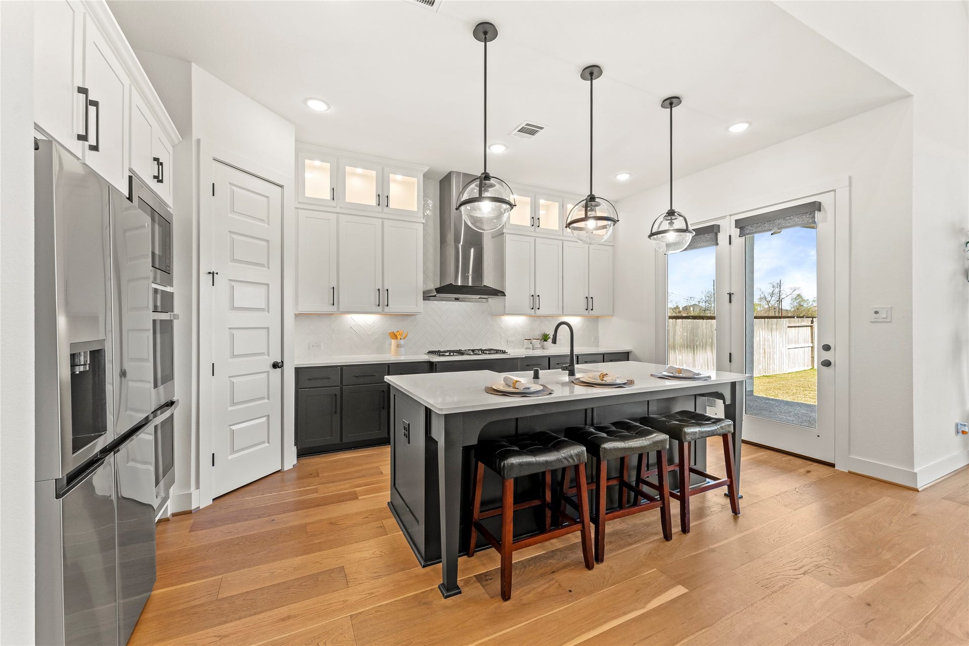 1934 Pleasant Grove Drive, Missouri City, TX 77459 The centerpiece is a stunning gourmet island featuring a deep farmhouse sink, sleek black cabinetry, and comfortable seating for three, perfect for casual morning coffee or interactive meal prep.