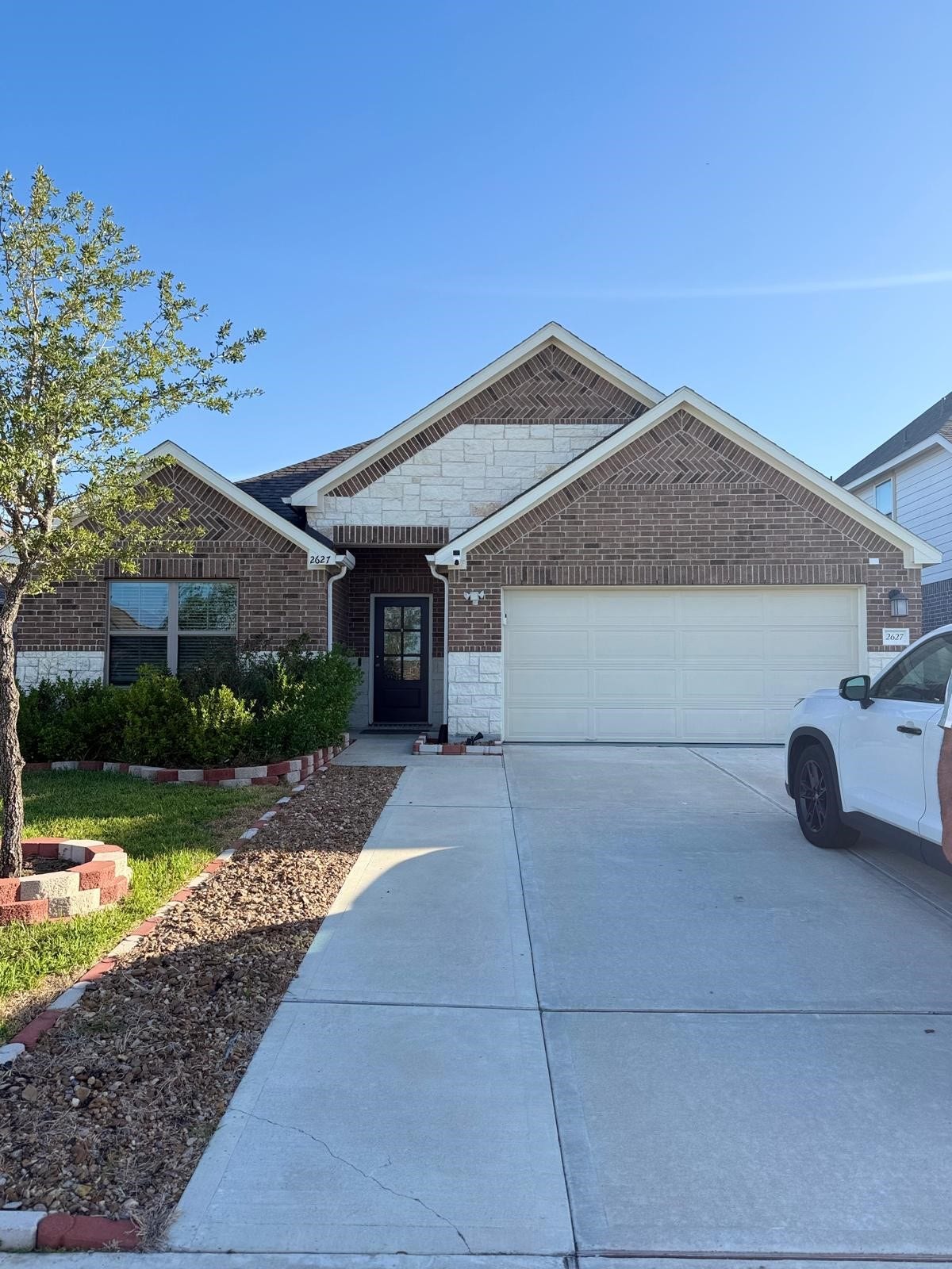 2627 Westward Hill Dr, Fresno, TX 77545 Charming brick home with a spacious two-car garage, manicured landscaping, and inviting entryway.