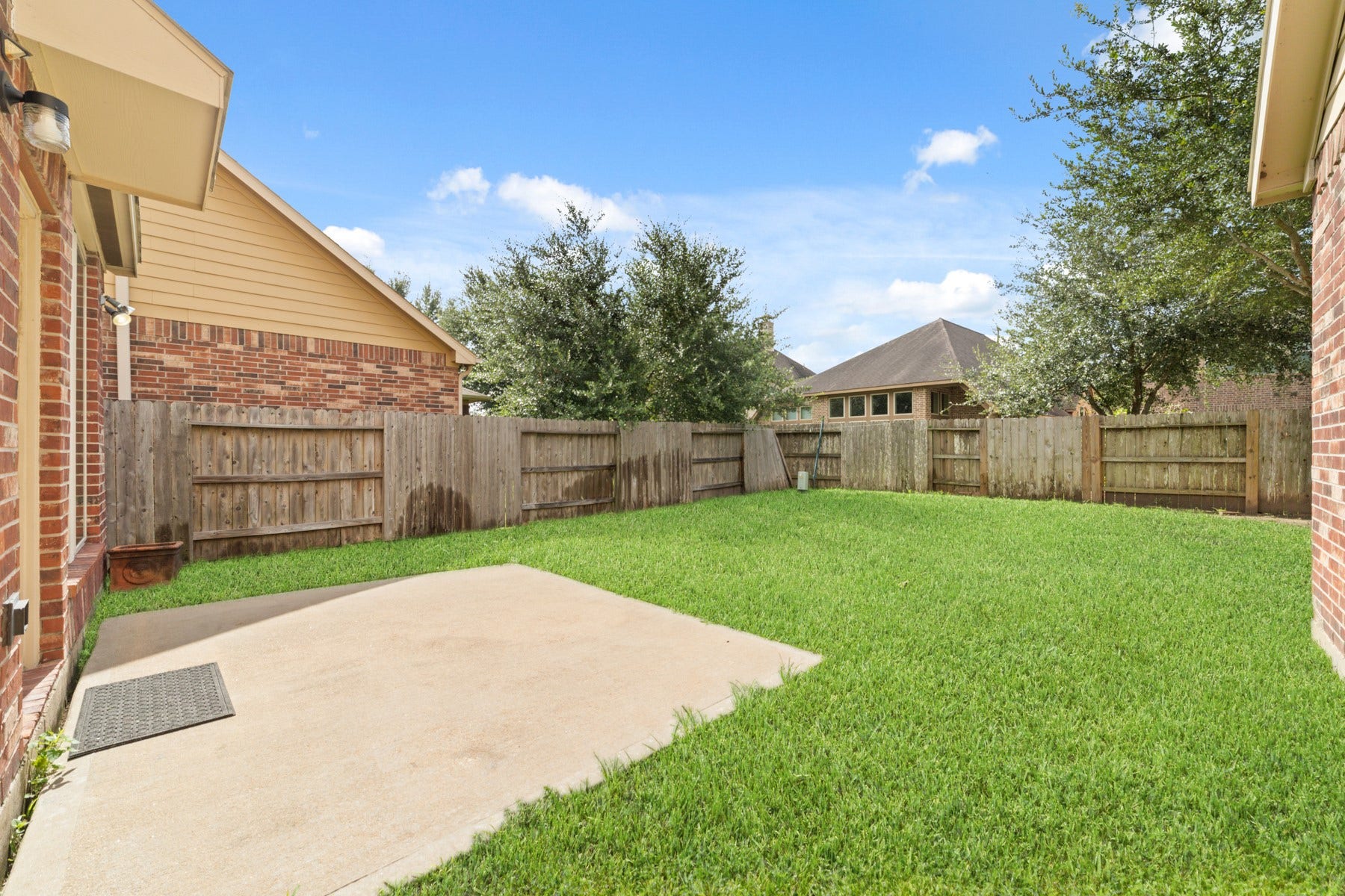 This inviting backyard set against a backdrop of bright blue skies and lush greenery.
