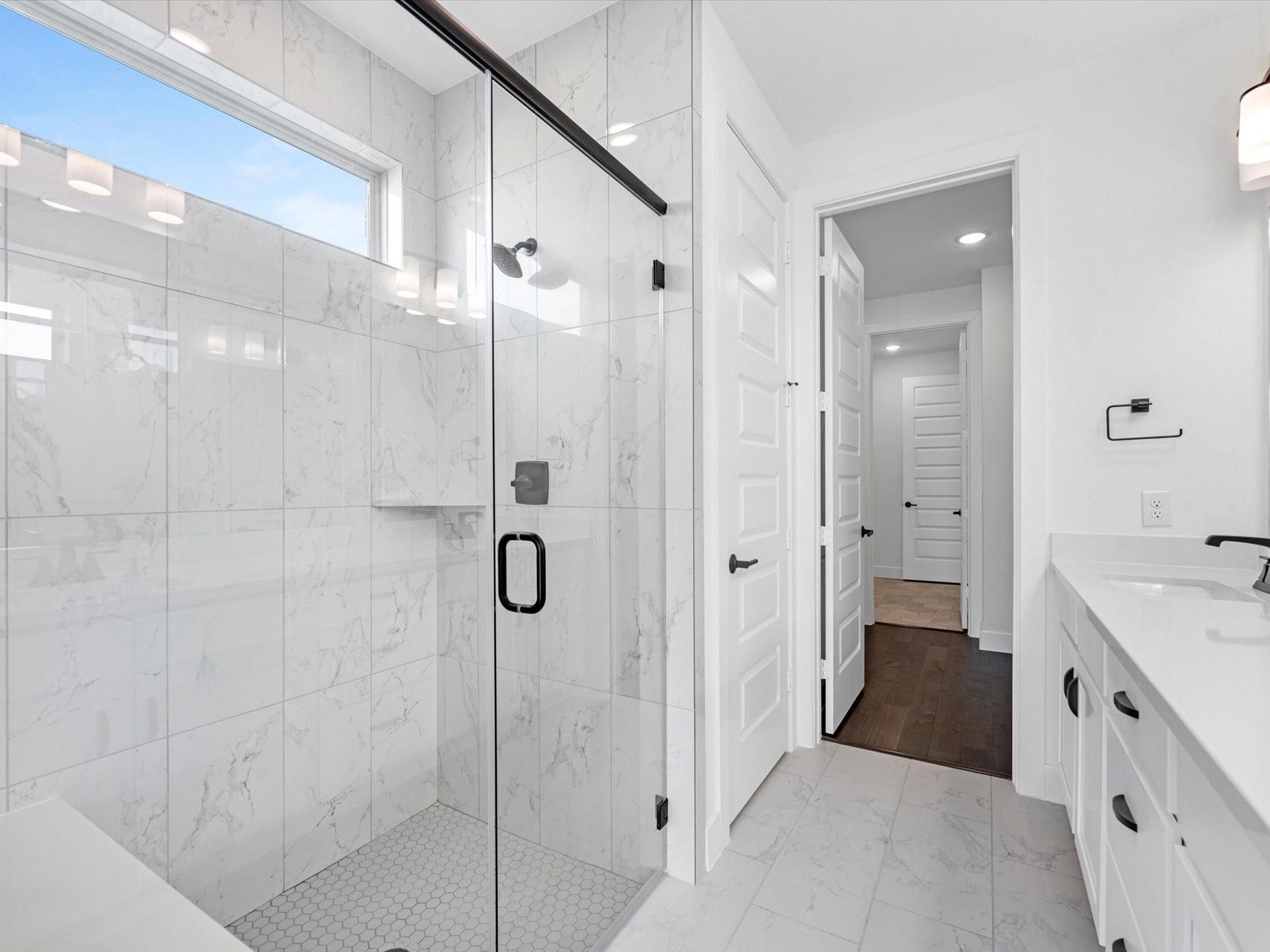 7307 Winding Aster Way, Katy, TX 77493 A master full bath with stunning white tile seamlessly connects to a wood-accented walk-in closet, which leads directly to the laundry room. Imagine how convenient it is for the owners whenever they need to wash, dry, or fold their laundry.