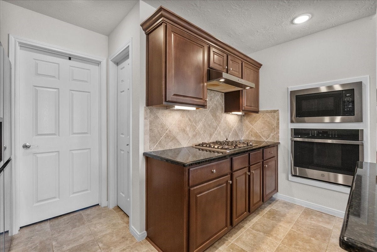 2111 Gilbert Road, Dickinson, TX 77539 Chef's eat-in island kitchen features 42" cabinets with crown molding, granite countertops, stainless steel appliances and a breakfast bar