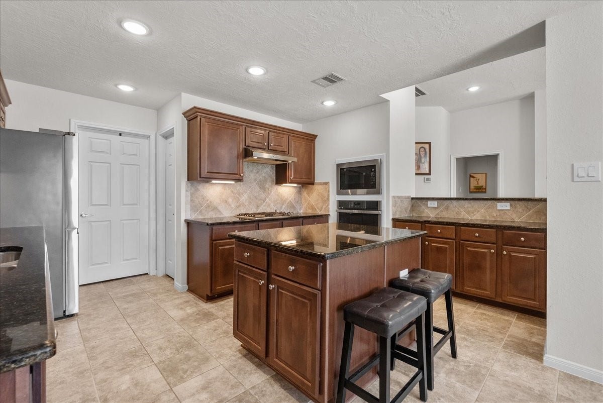 2111 Gilbert Road, Dickinson, TX 77539 Chef's eat-in island kitchen features 42" cabinets with crown molding, granite countertops, stainless steel appliances and a breakfast bar