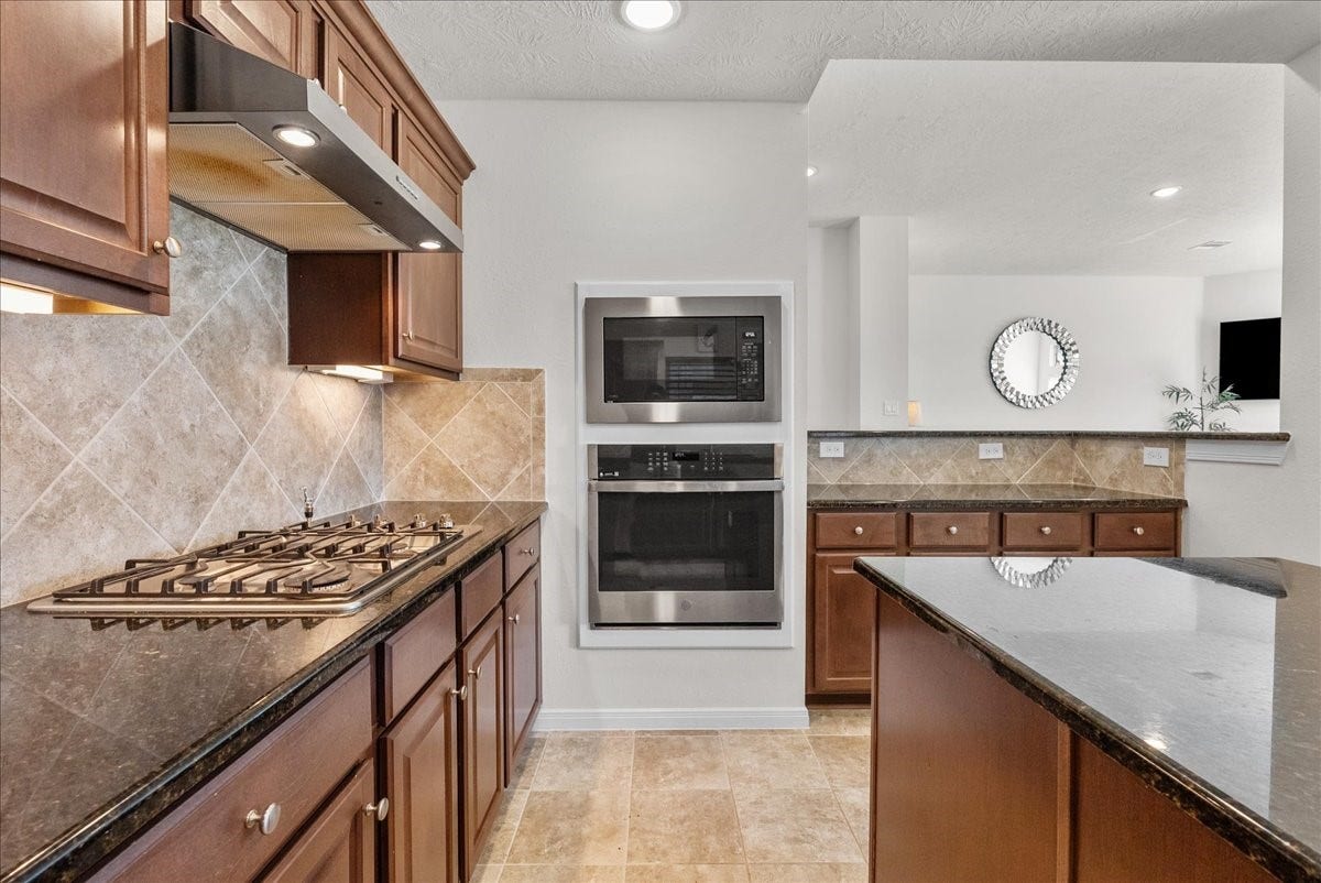 2111 Gilbert Road, Dickinson, TX 77539 Chef's eat-in island kitchen features 42" cabinets with crown molding, granite countertops, stainless steel appliances and a breakfast bar