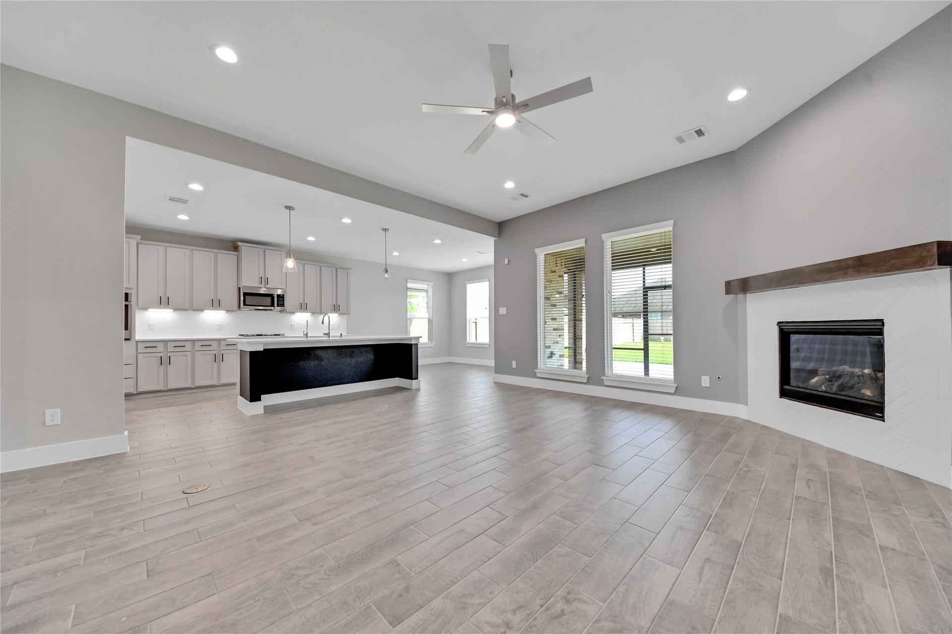 23619 Iris Field Court, Katy, TX 77493 Open-concept kitchen and living area featuring a spacious island, quartz countertops, pendant lighting, and seamless flow into the family room with fireplace.